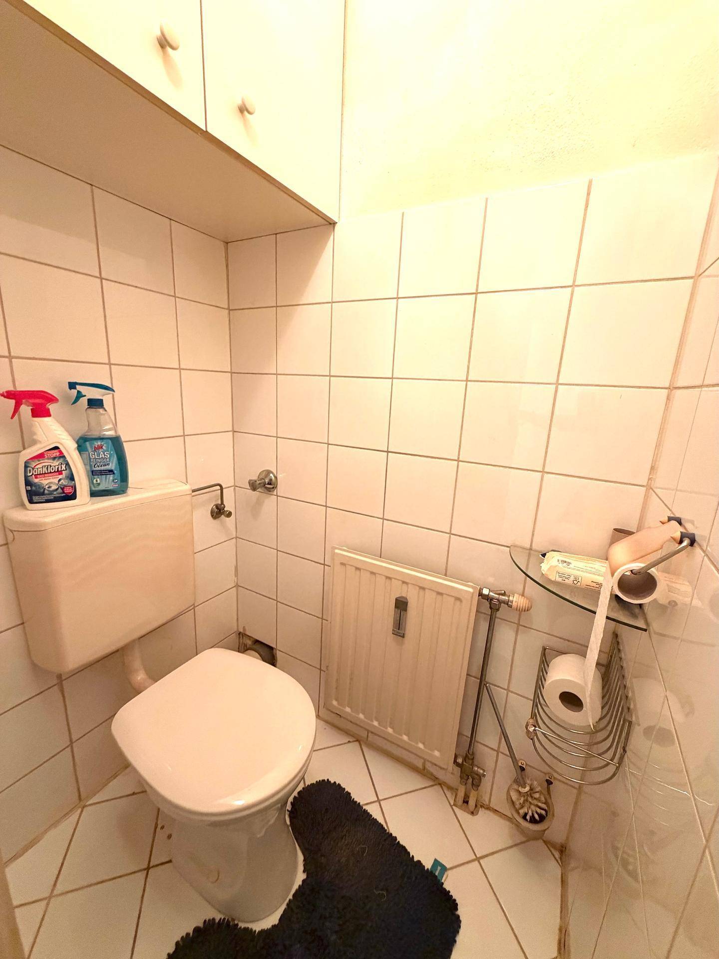 Separates WC mit Fliesen an Wänden und Boden, sowie einem Heizkörper.
