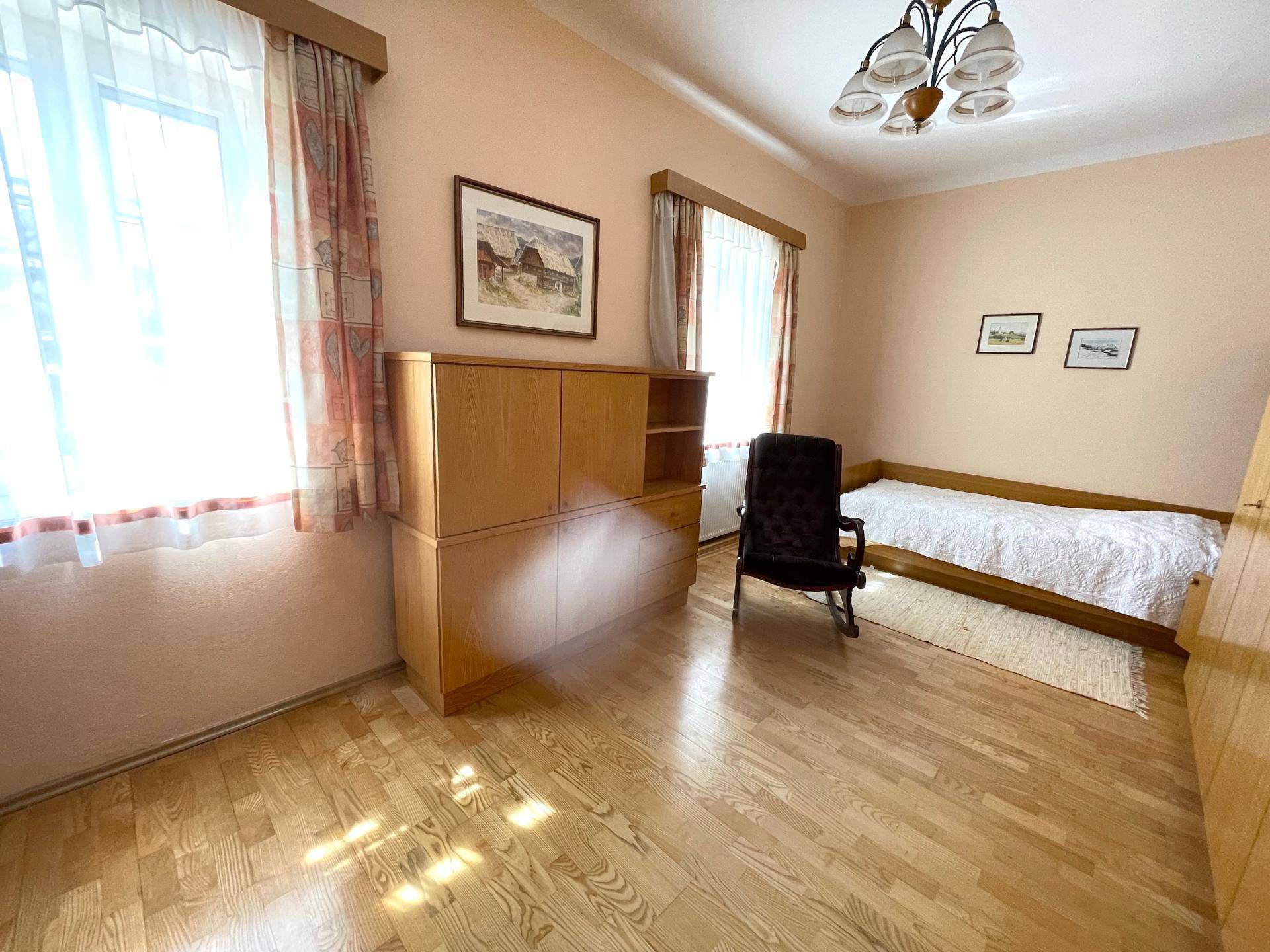 Helles Schlafzimmer mit Parkettboden, Einzelbett und großem Fenster.