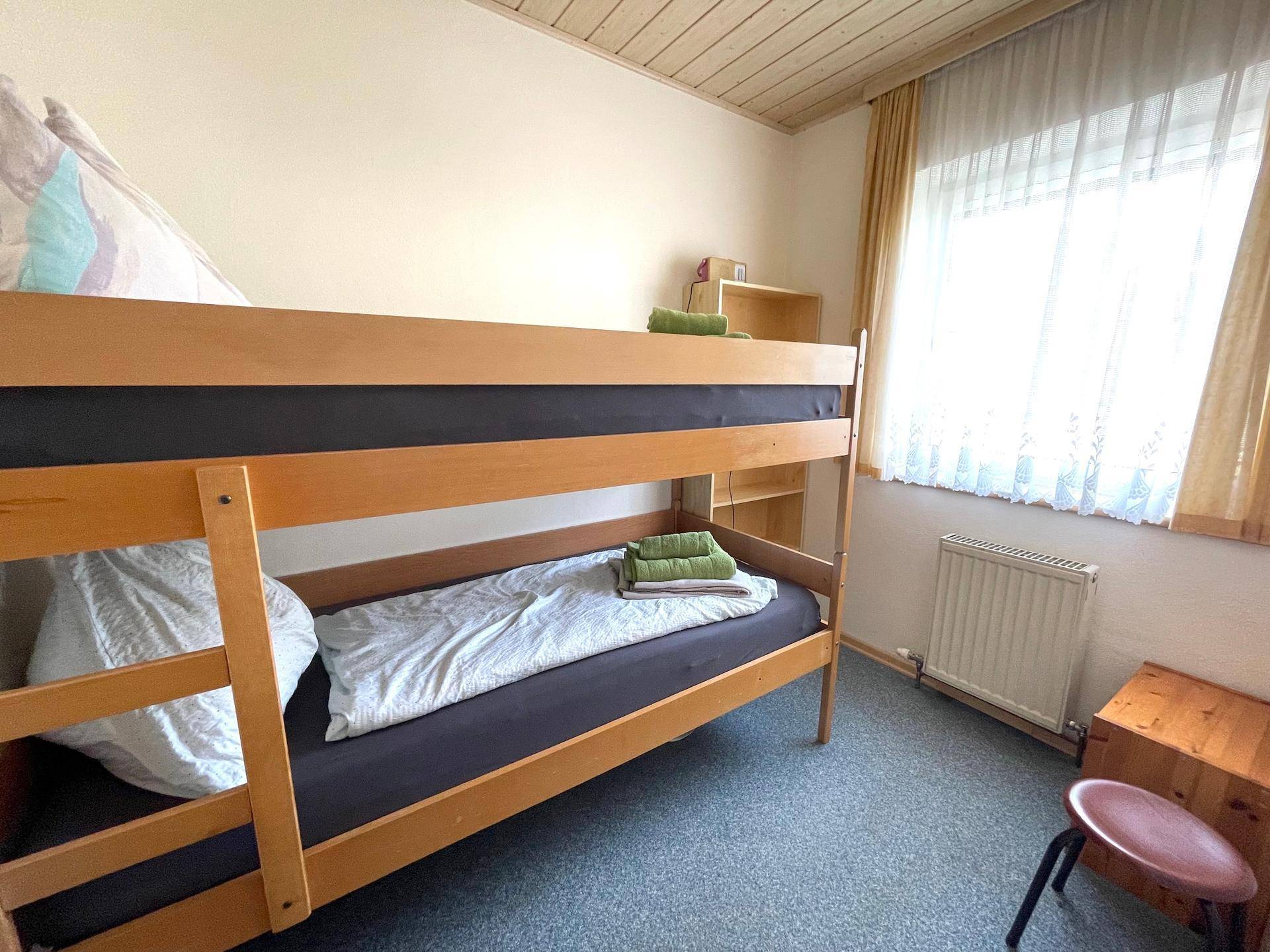 Ein Schlafzimmer mit Etagenbett, Teppichboden und einer Holzdecke.