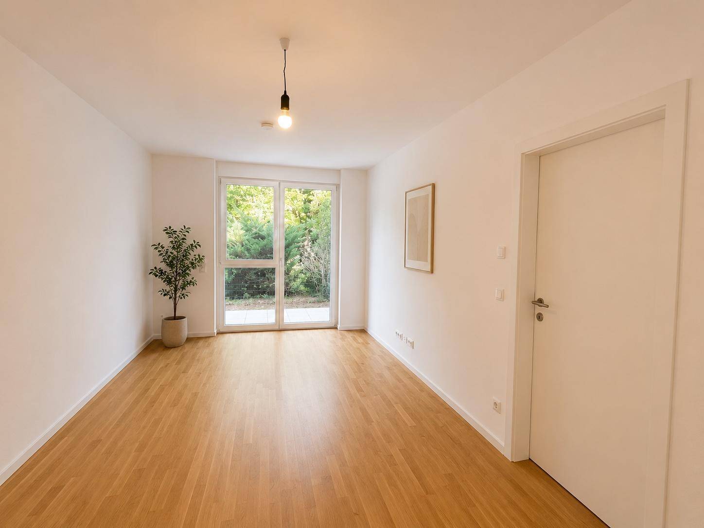 Geräumiges Wohnzimmer mit hellem Holzfußboden und großen Glastüren, die Zugang zum Garten bieten.