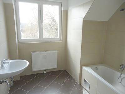 Helles Badezimmer mit Badewanne, Waschbecken und Fenster für Tageslicht.