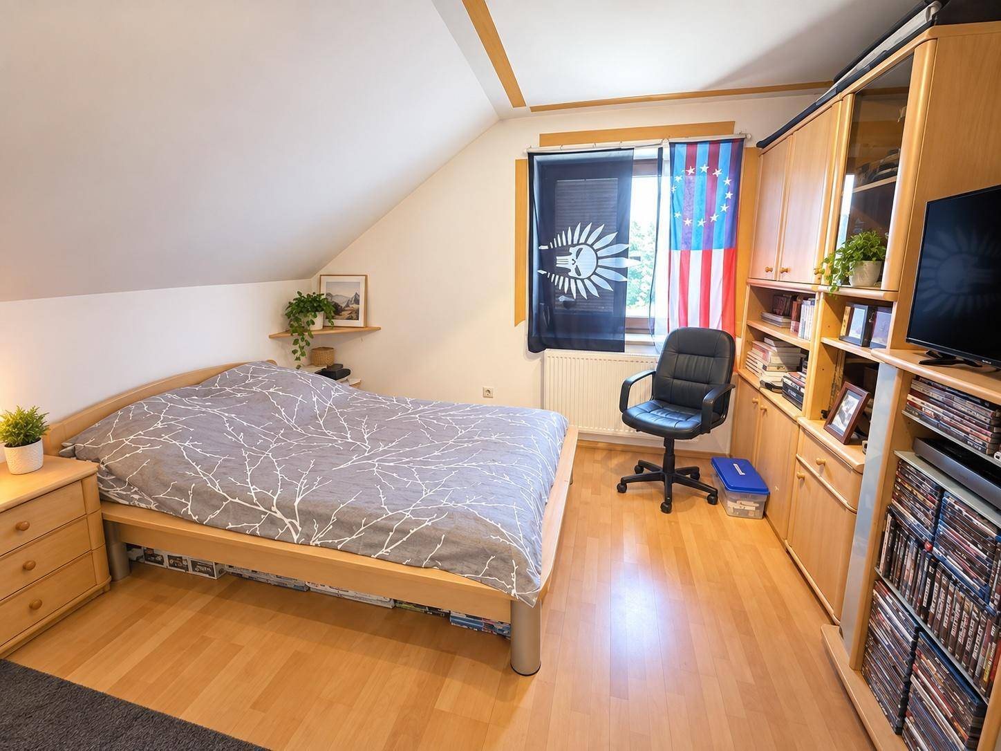 Schlafzimmer im Dachgeschoss mit Holzbett, Schrankwand und Laminatboden.