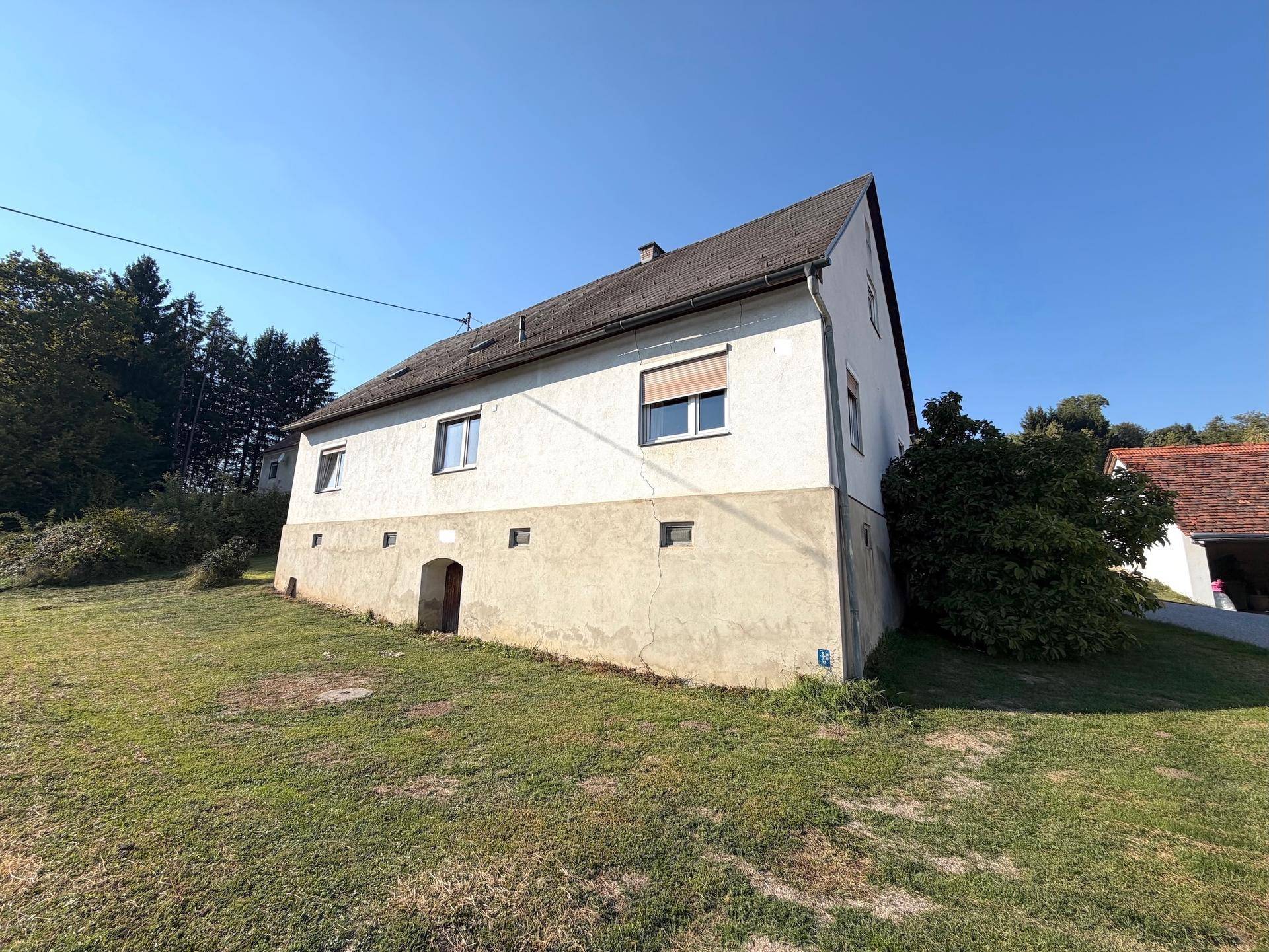 Einfamilienhaus mit weißer Fassade und Satteldach in sonniger Lage.
