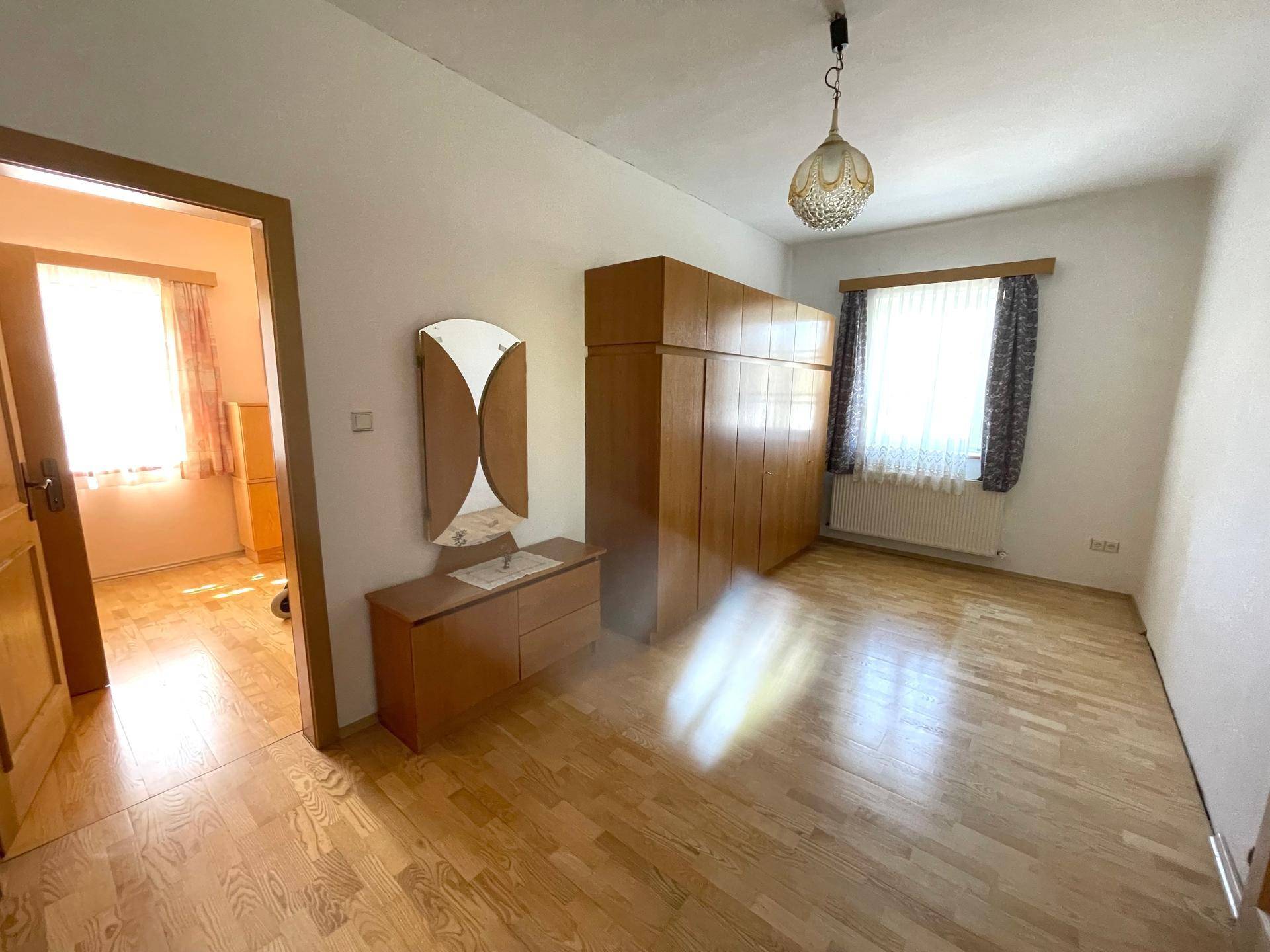 Geräumiges Schlafzimmer mit Parkettboden, Kleiderschrank und viel Tageslicht.