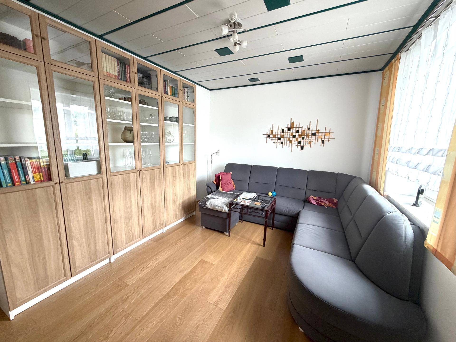 Gemütliches Wohnzimmer mit großem Ecksofa, Vitrinenschränken und Laminatboden.