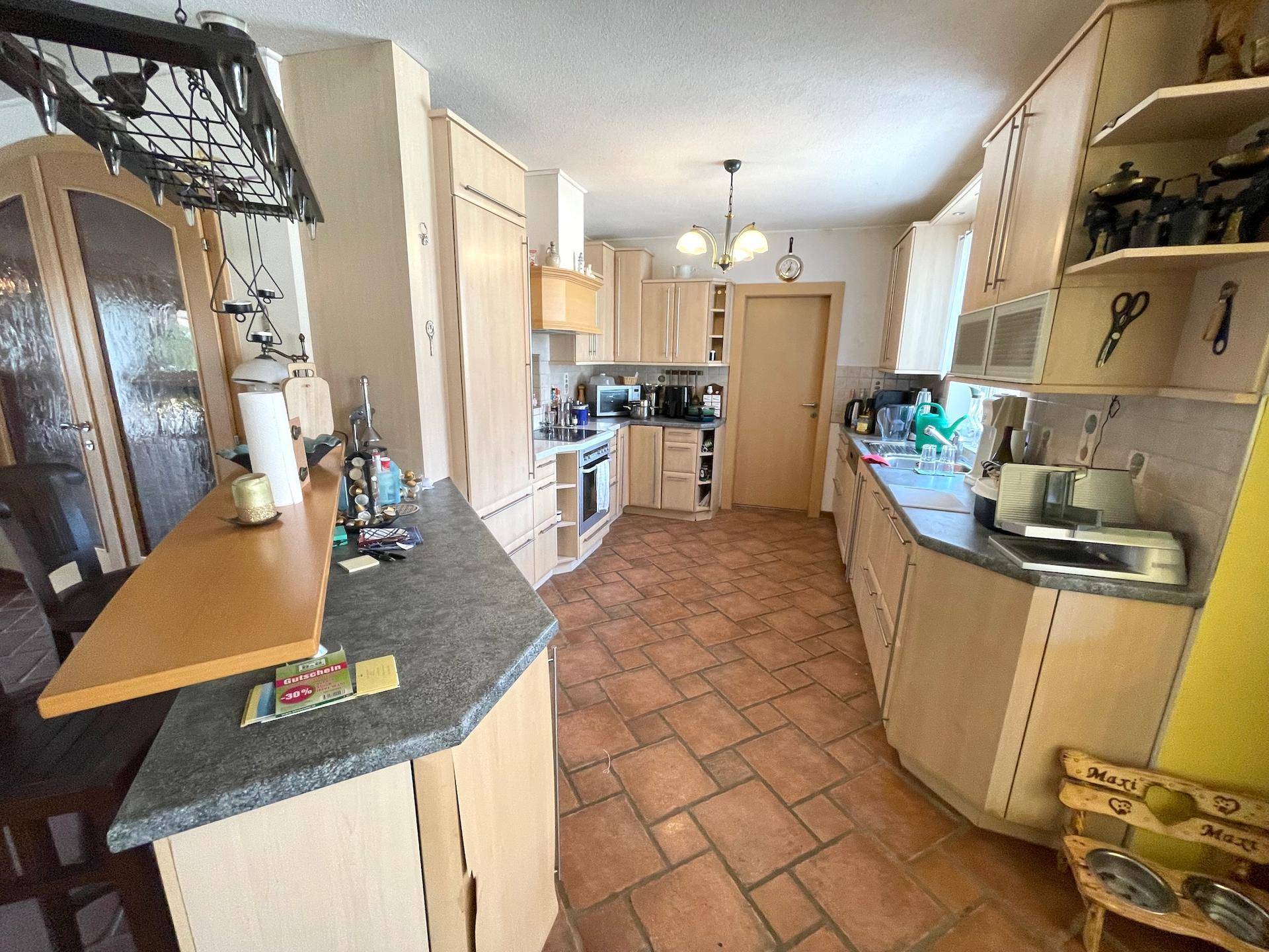 Eine traditionelle Küche mit Holzschränken, Granitarbeitsplatten und Terrakottaboden.