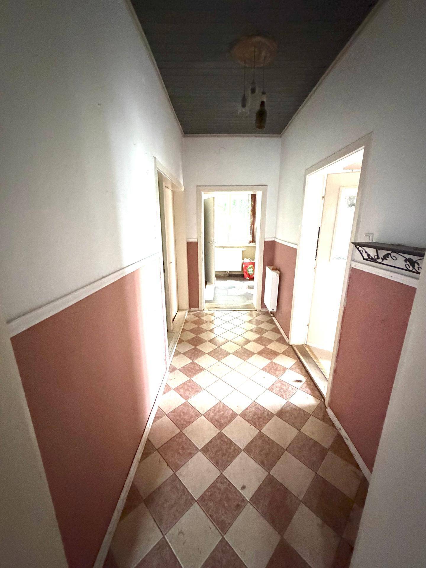 Flur mit gemustertem Fliesenboden und Holzdecke, führt zu weiteren Räumen.