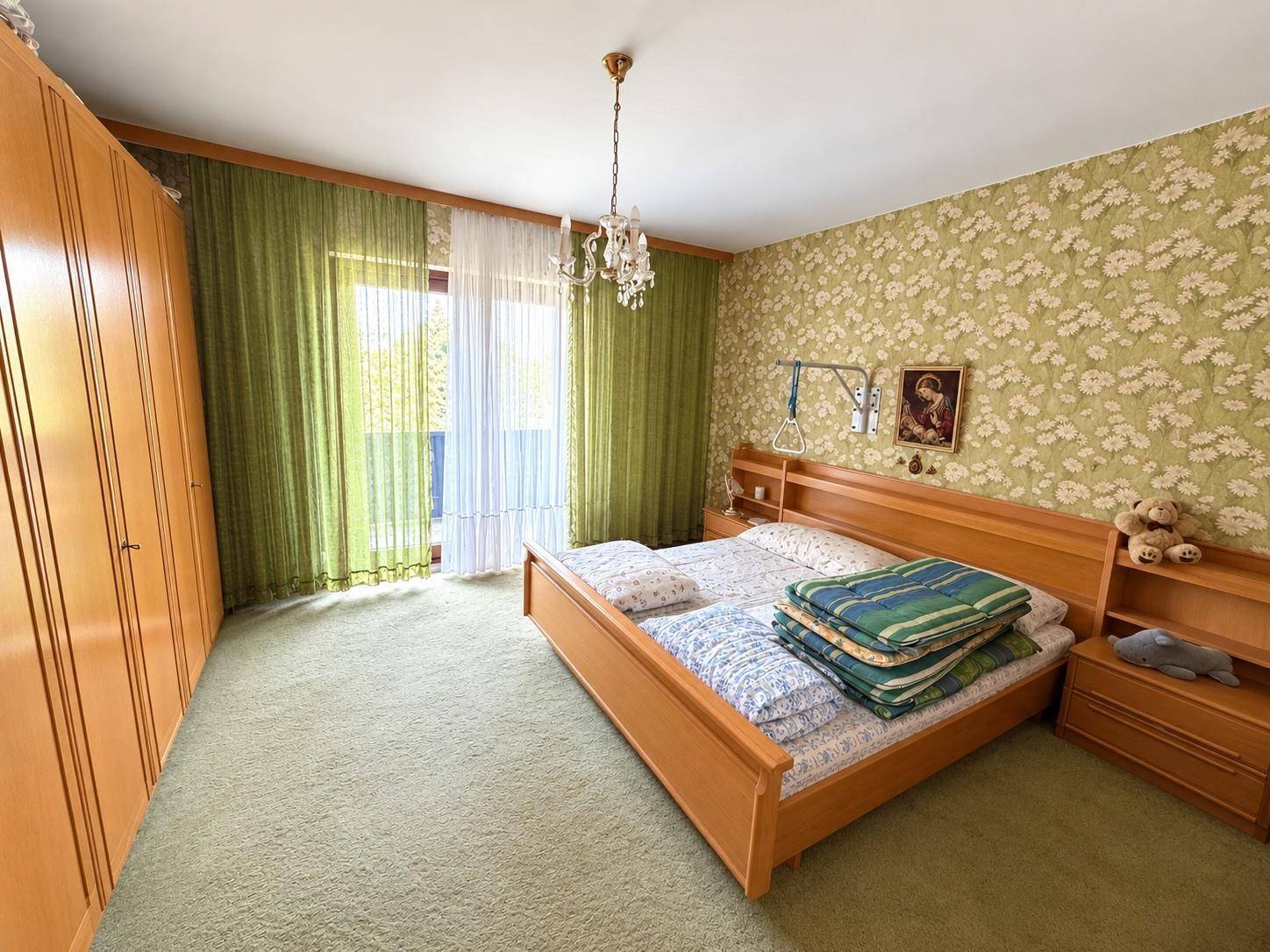 Helles Schlafzimmer mit Doppelbett, Teppichboden und Zugang zum Balkon.