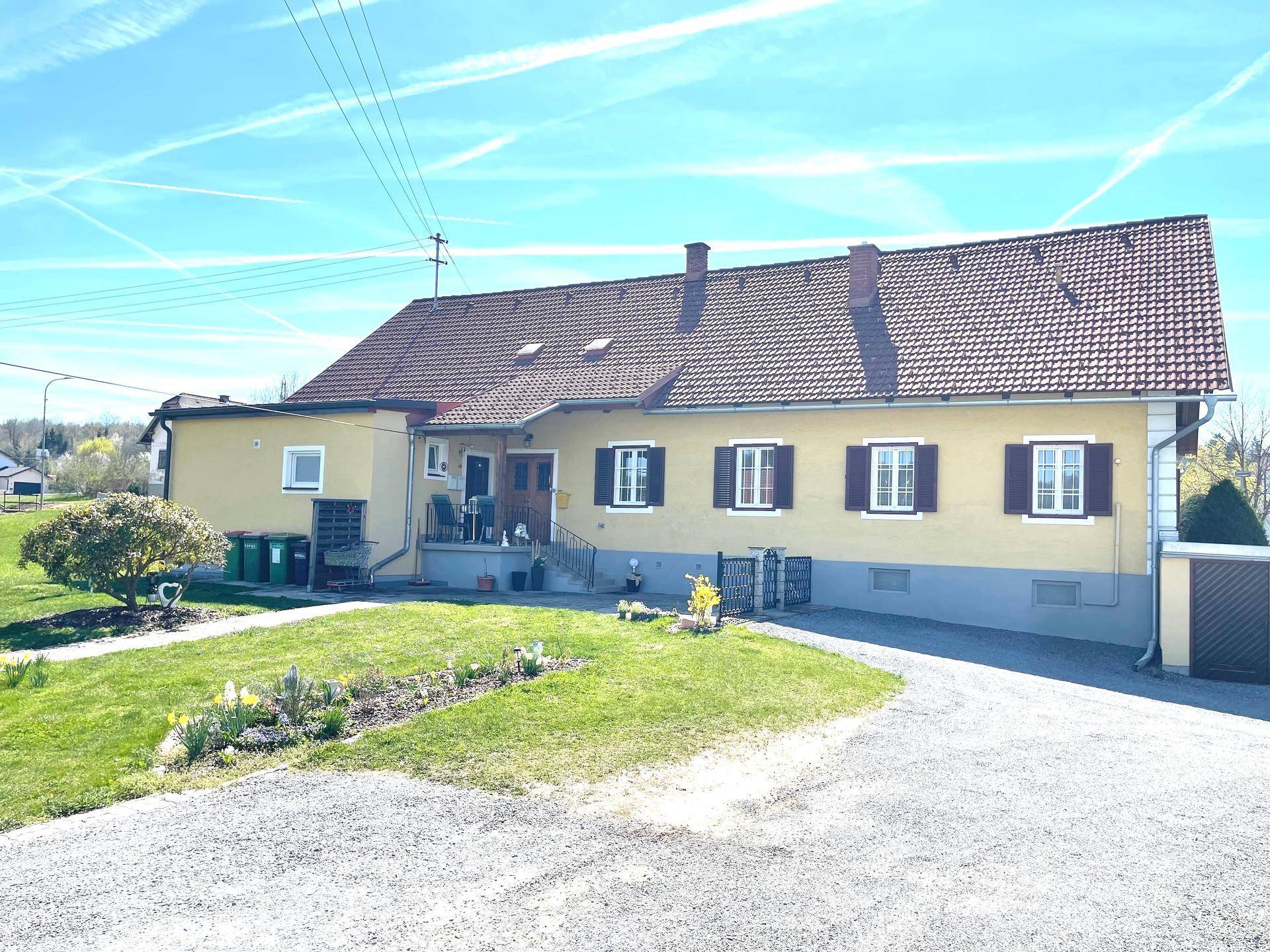 Rückansicht des Hauses mit kleiner Terrasse, Garten und ländlicher Umgebung.
