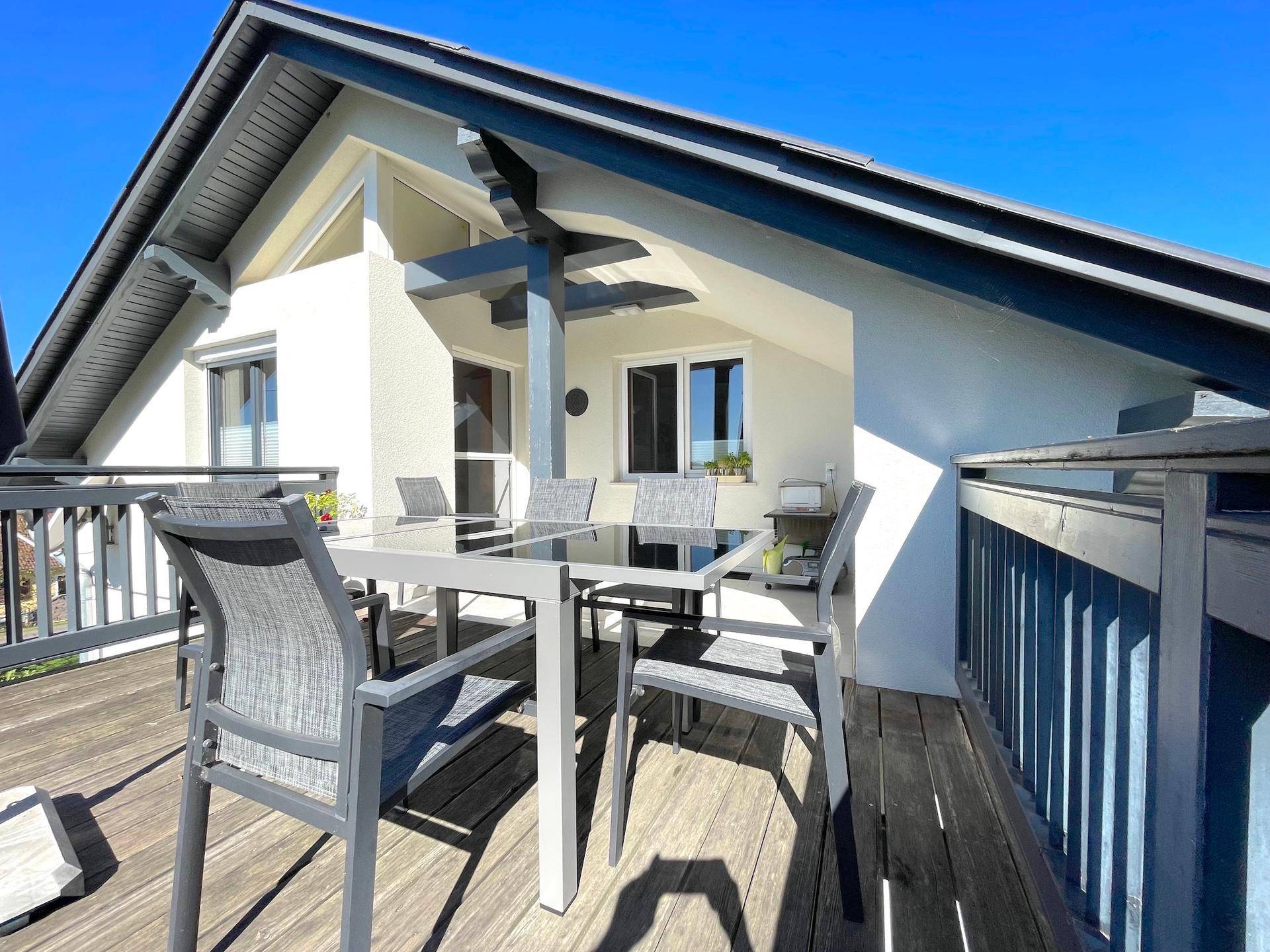 Geräumiger Balkon mit Holzboden und Gartenmöbeln, bietet einen schönen Blick auf die Umgebung.