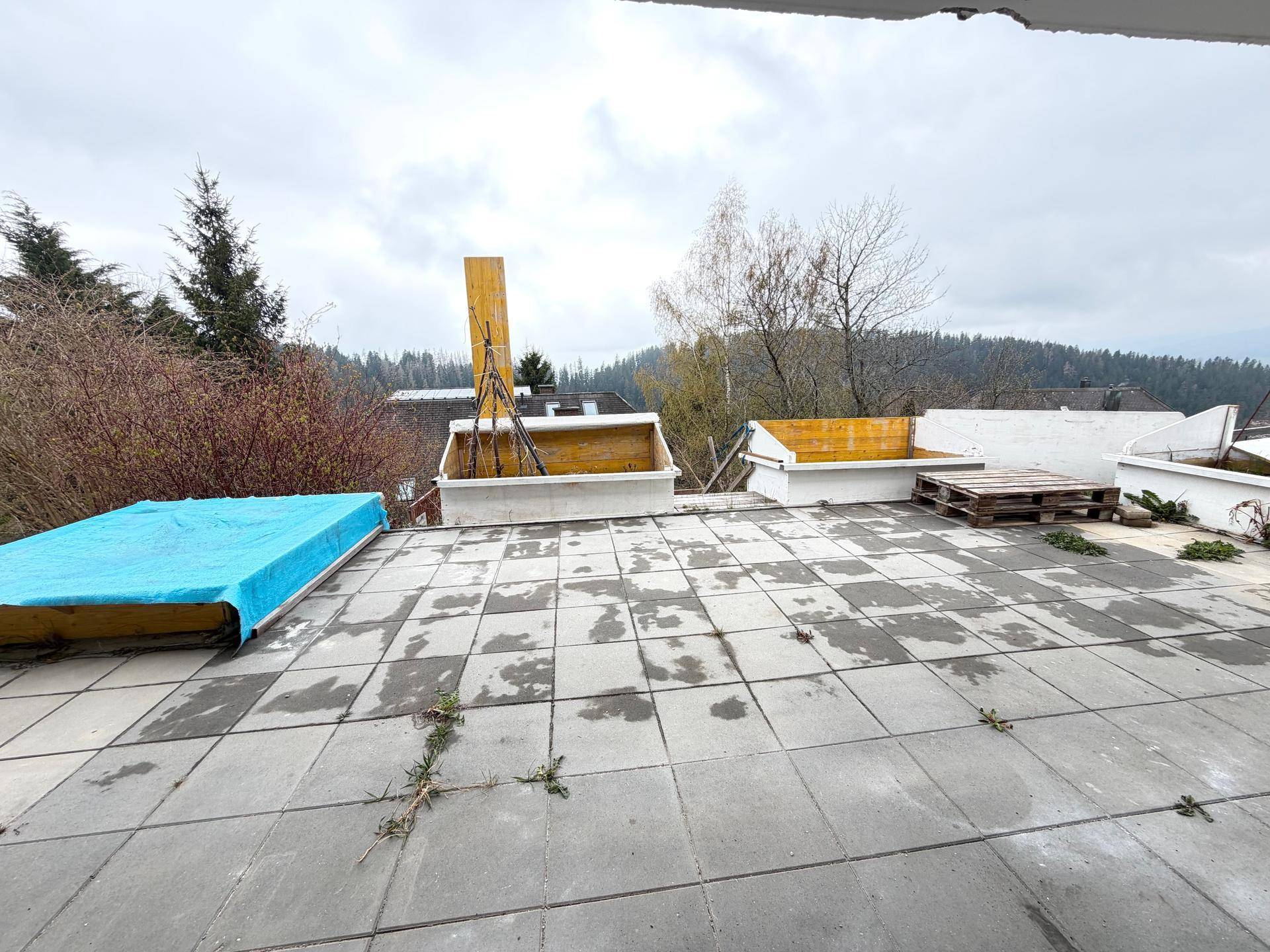 Große Außenterrasse mit Steinplatten und Blick auf die umliegende Natur und das Haus.