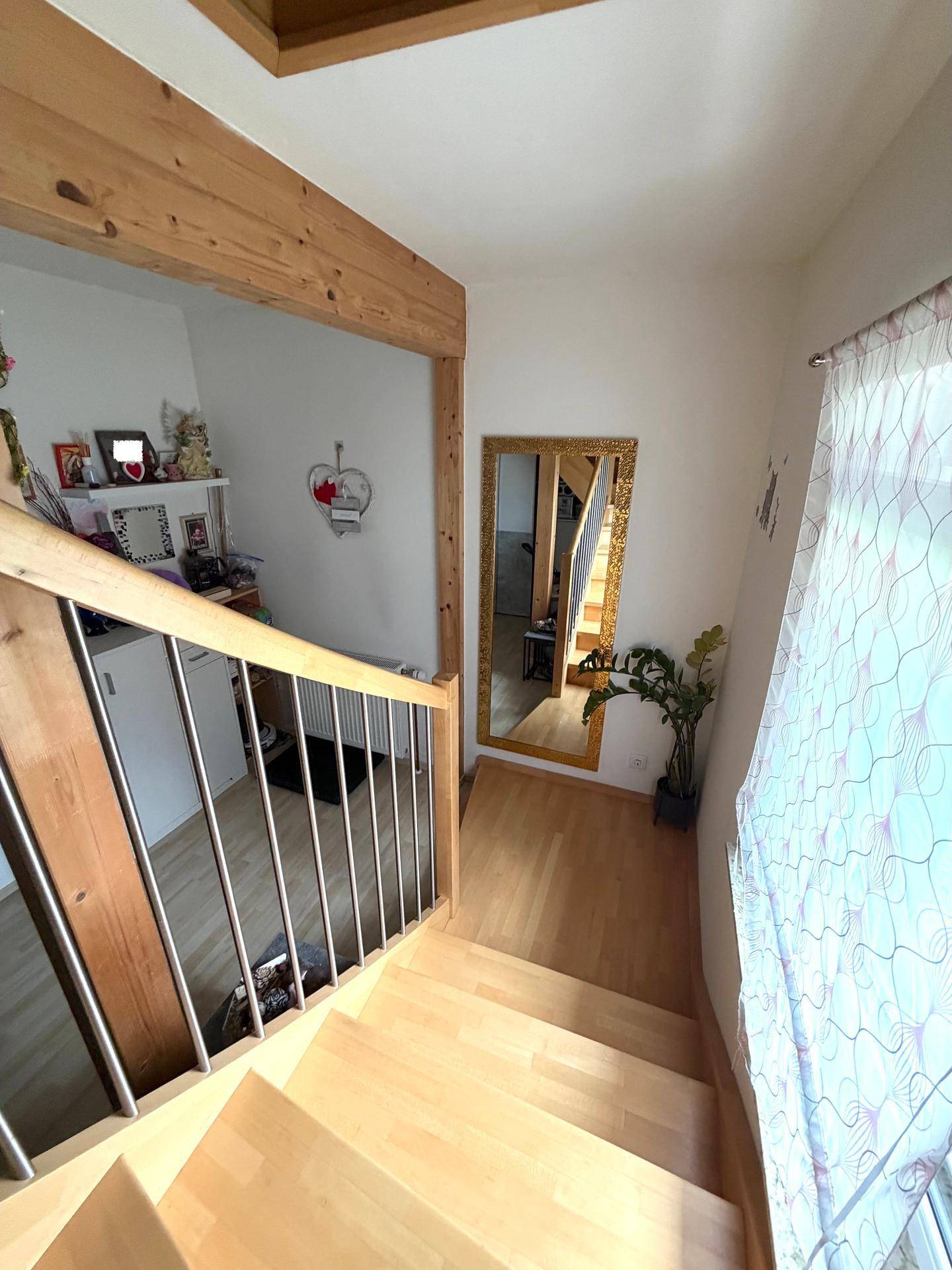 Holztreppe mit Metallgeländer und großem Spiegel im Treppenhaus.