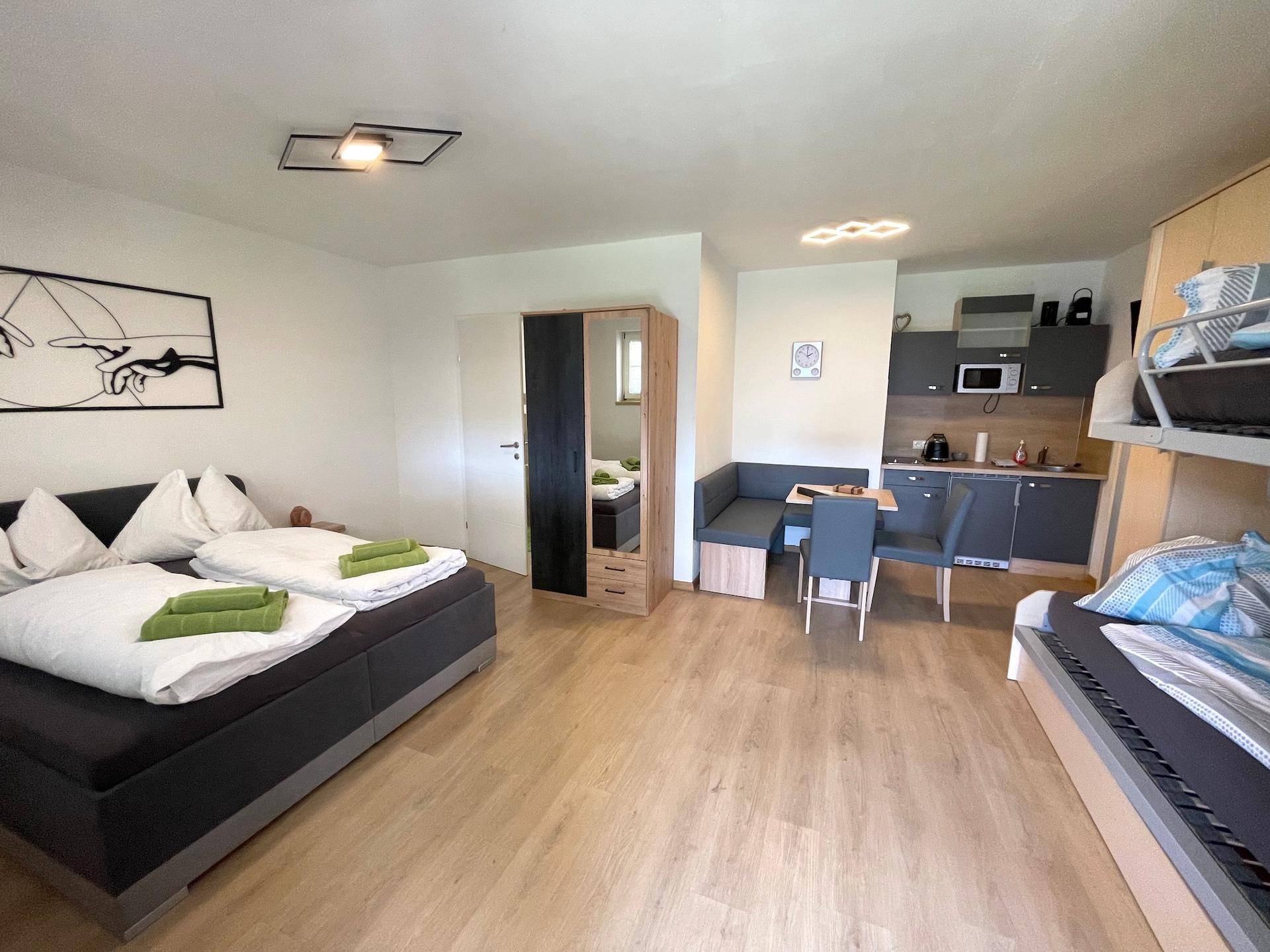 Ein offenes Studio-Apartment mit Küchenzeile, Essbereich und Schlafbereich inklusive Etagenbett.