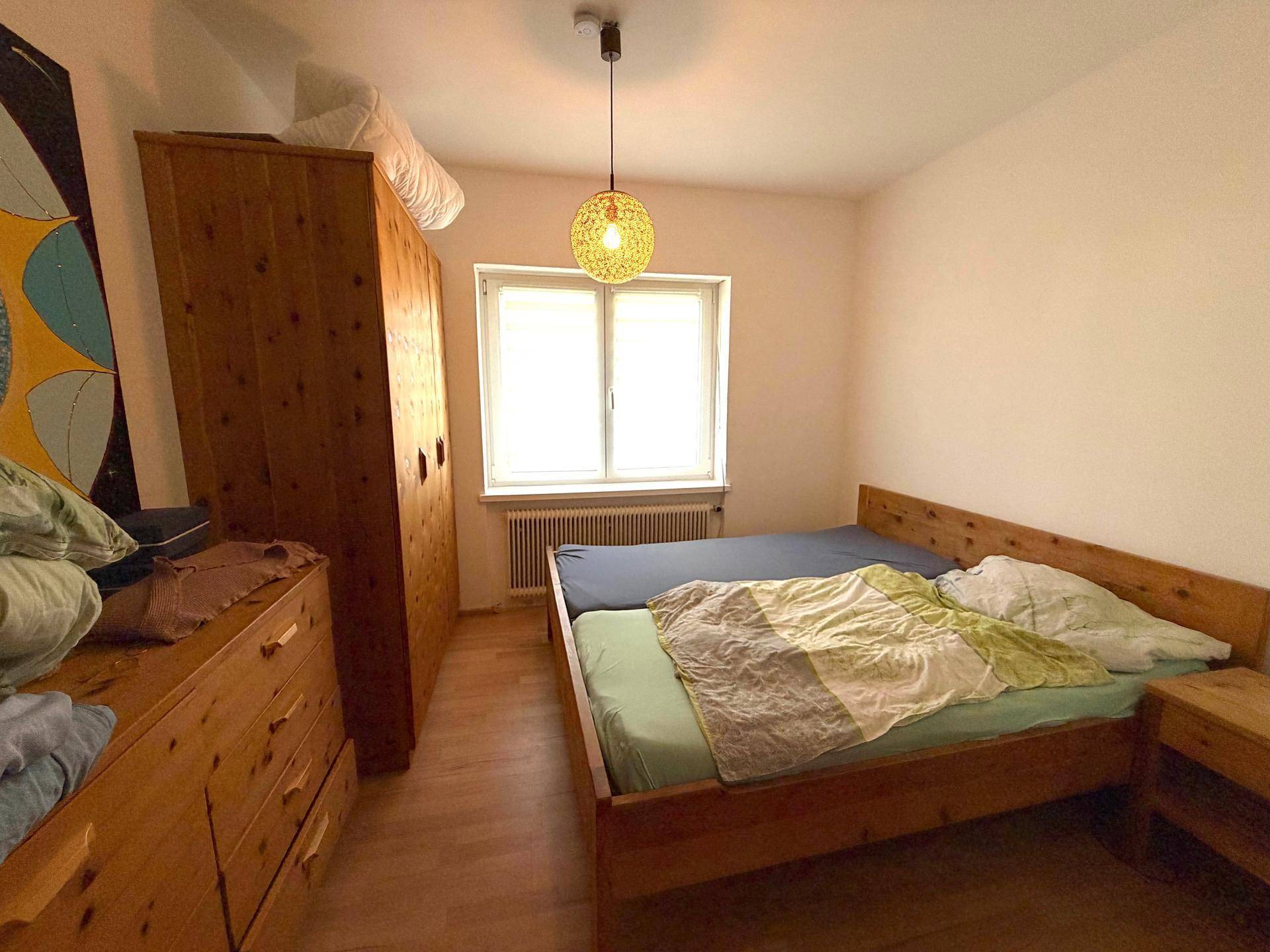 Gemütliches Schlafzimmer mit Holzbett, passendem Kleiderschrank und Fenster.