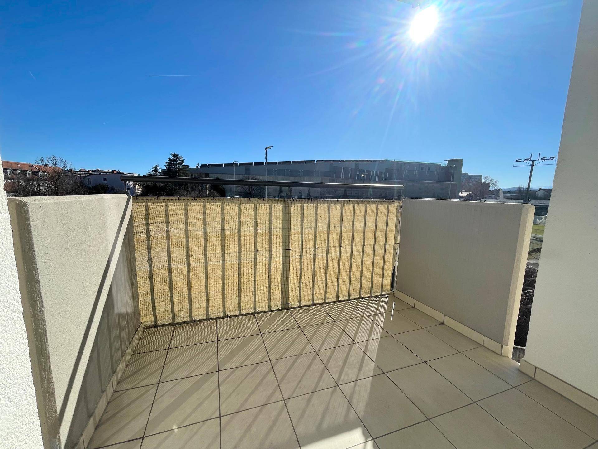 Sonniger Balkon mit Fliesenboden und Sichtschutz, ideal zum Entspannen.
