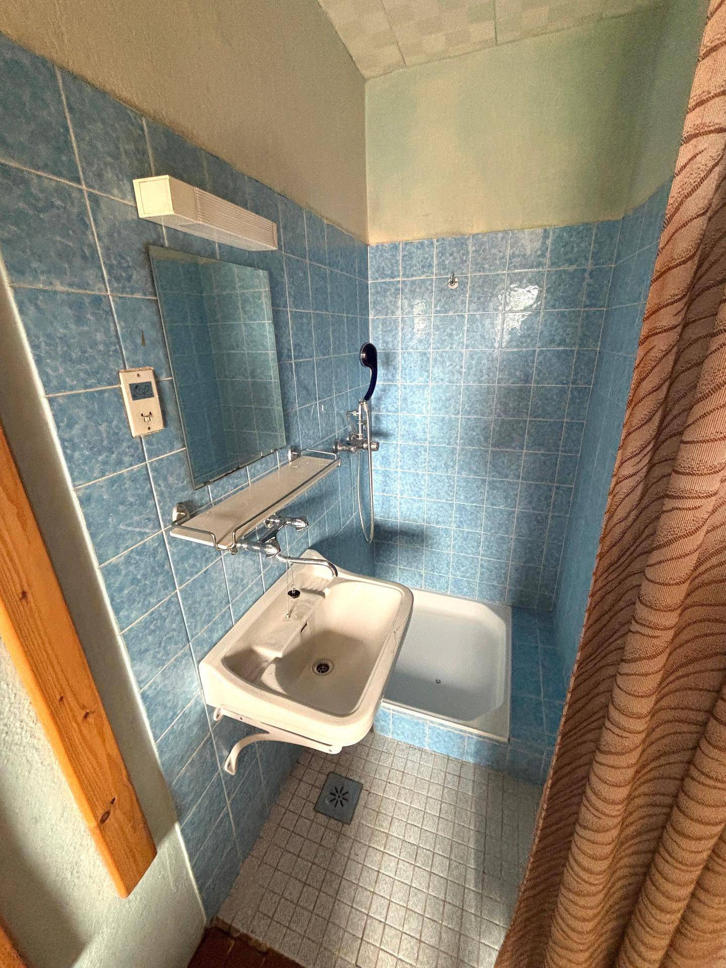 Kleines Badezimmer mit blauen Fliesen, Waschbecken und Duschwanne.