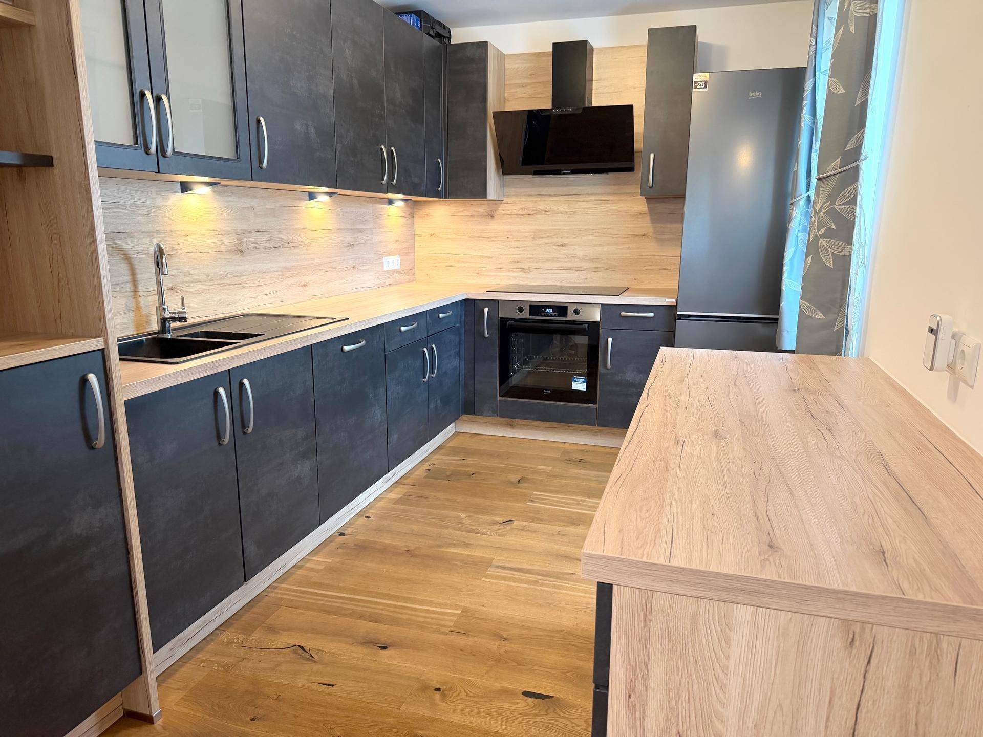 Helle Küche mit dunklen Schränken, Holzoptik-Arbeitsplatten und modernen Einbaugeräten.