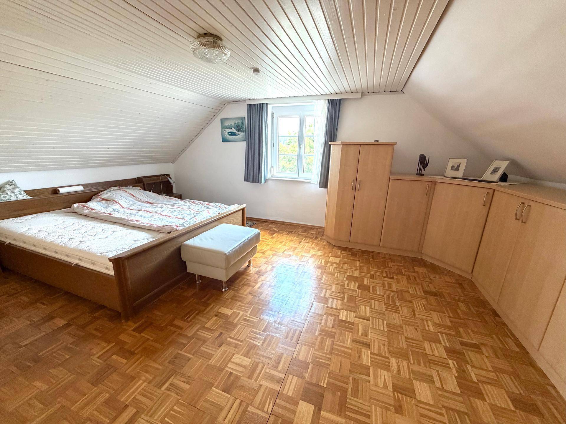 Geräumiges Schlafzimmer mit Doppelbett, Holzschränken und Parkettboden.