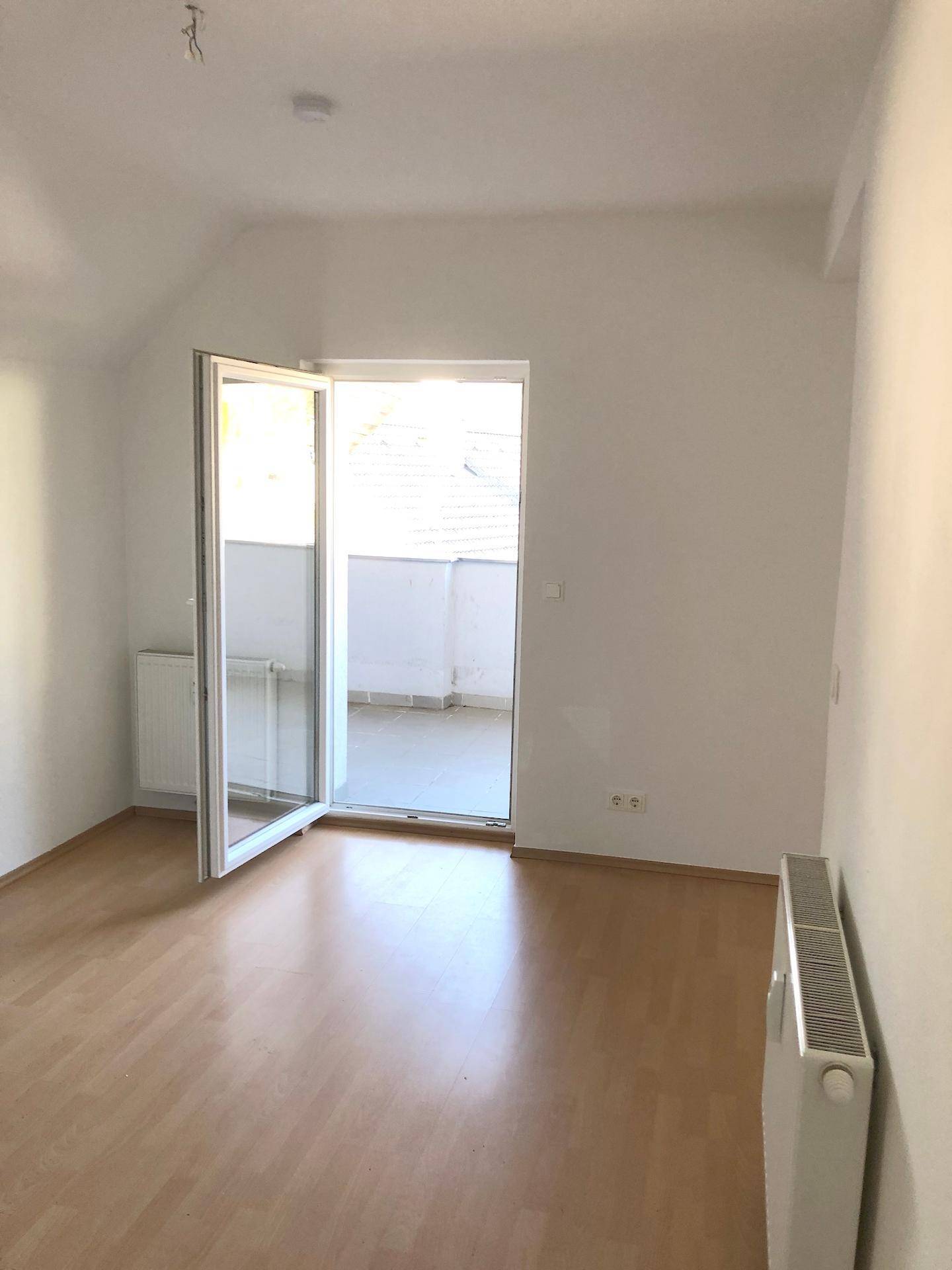Heller Wohnraum mit Laminatboden und direktem Zugang zu einem Balkon.