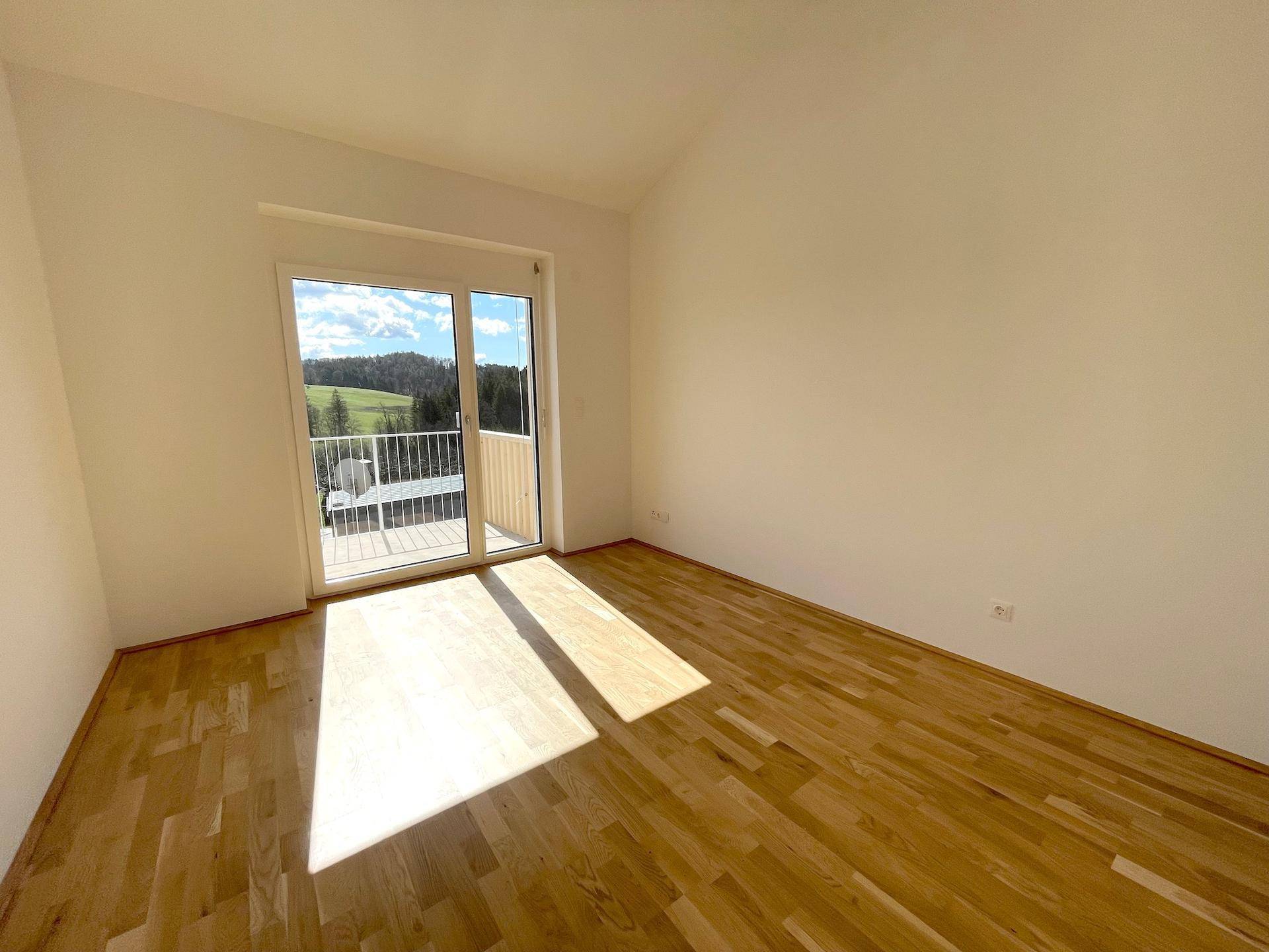 Helles Schlafzimmer mit Holzboden und direktem Zugang zu einem sonnigen Balkon.