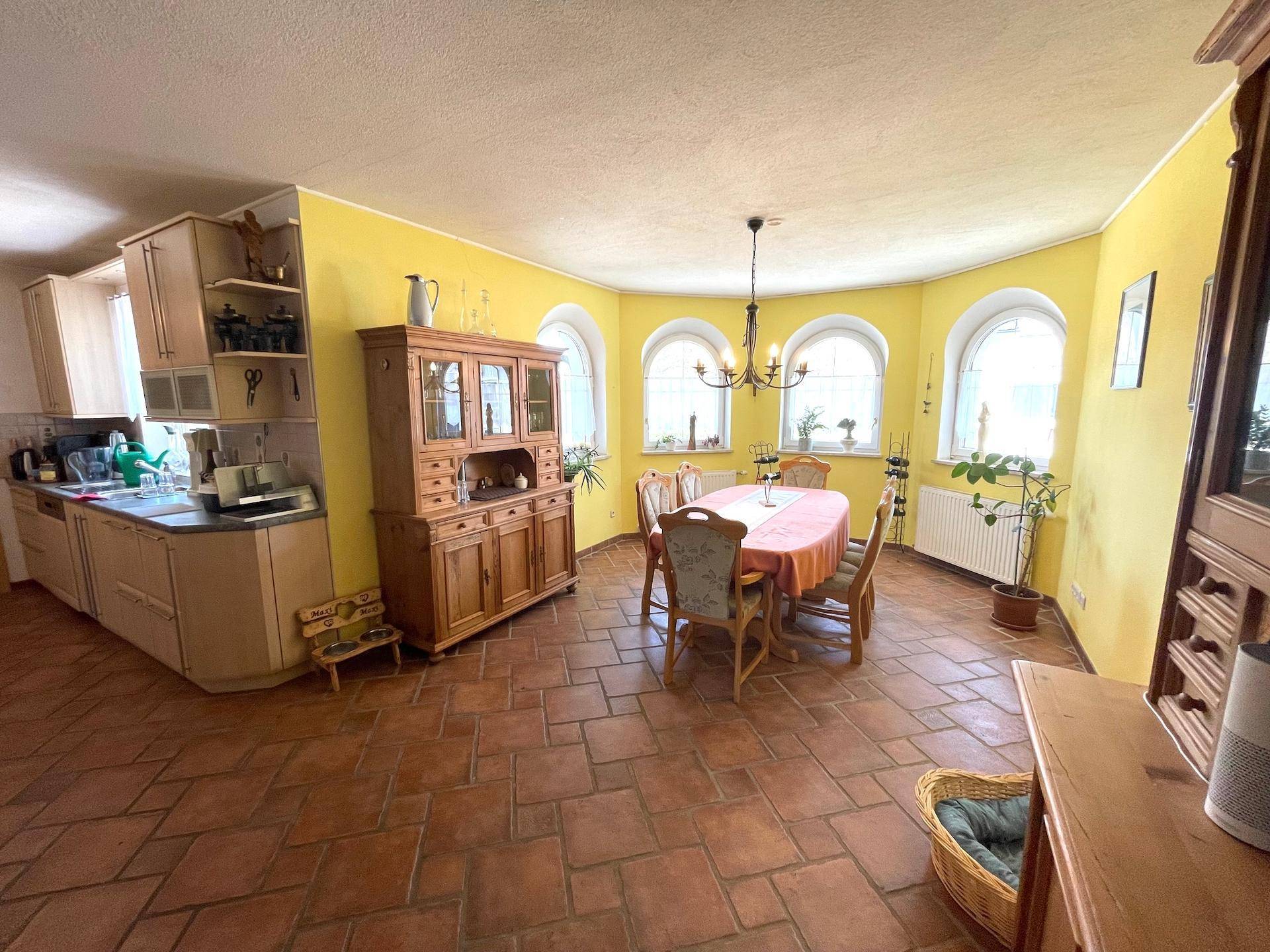 Eine geräumige Wohnküche mit Terrakottaboden, gelben Wänden und traditionellen Möbeln.