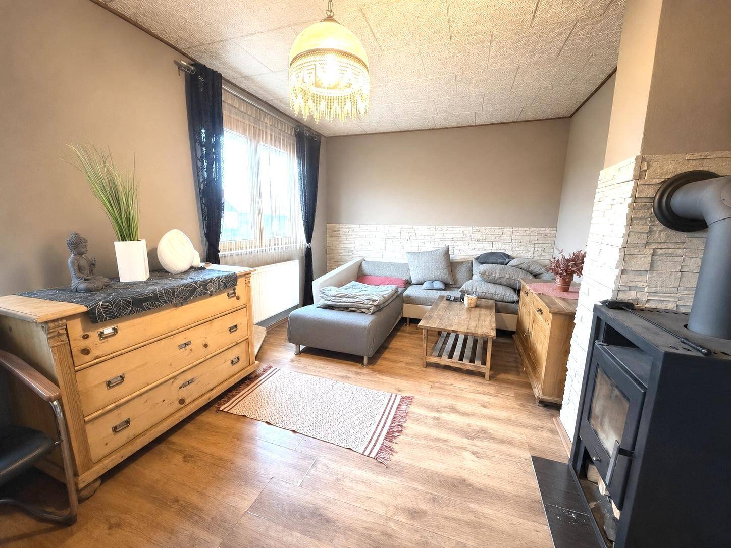 Gemütliches Wohnzimmer mit Sofa, Holzofen und traditionellen Holzmöbeln für entspannte Stunden.
