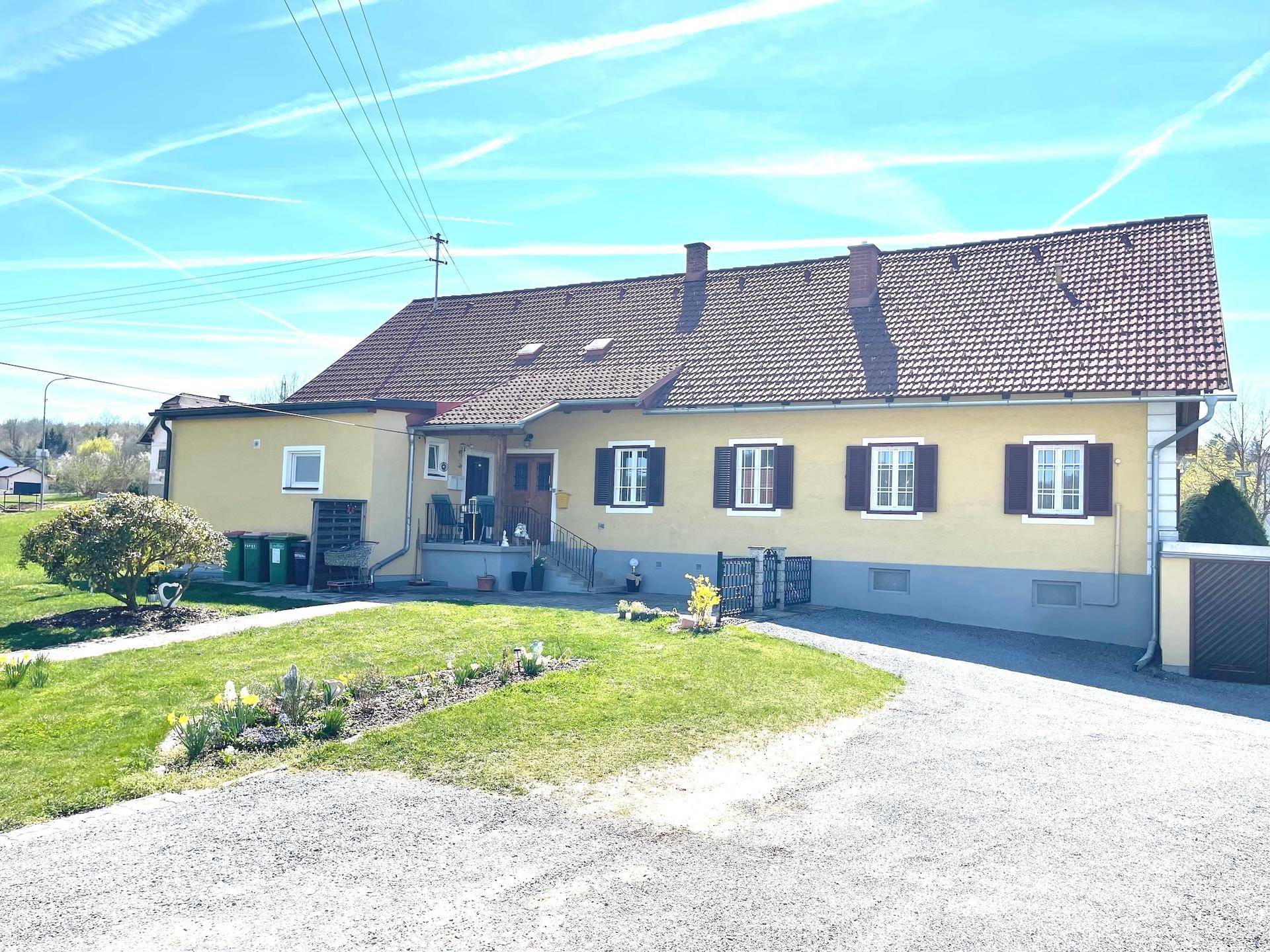 Rückansicht des Hauses mit Gartenbereich, Zufahrt und blauer Himmel.