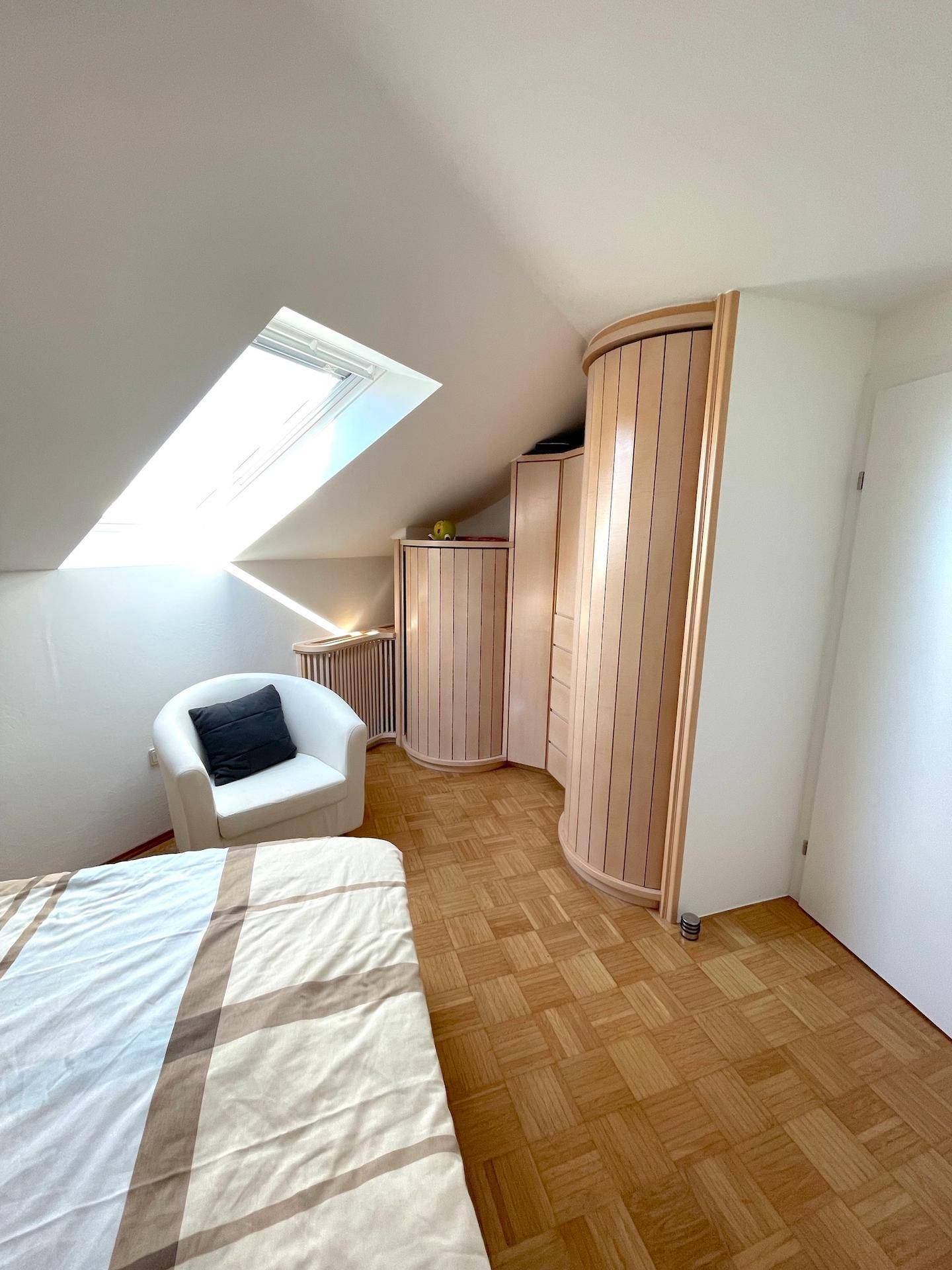 Helles Schlafzimmer im Dachgeschoss mit einzigartigen runden Kleiderschränken und Dachfenster.