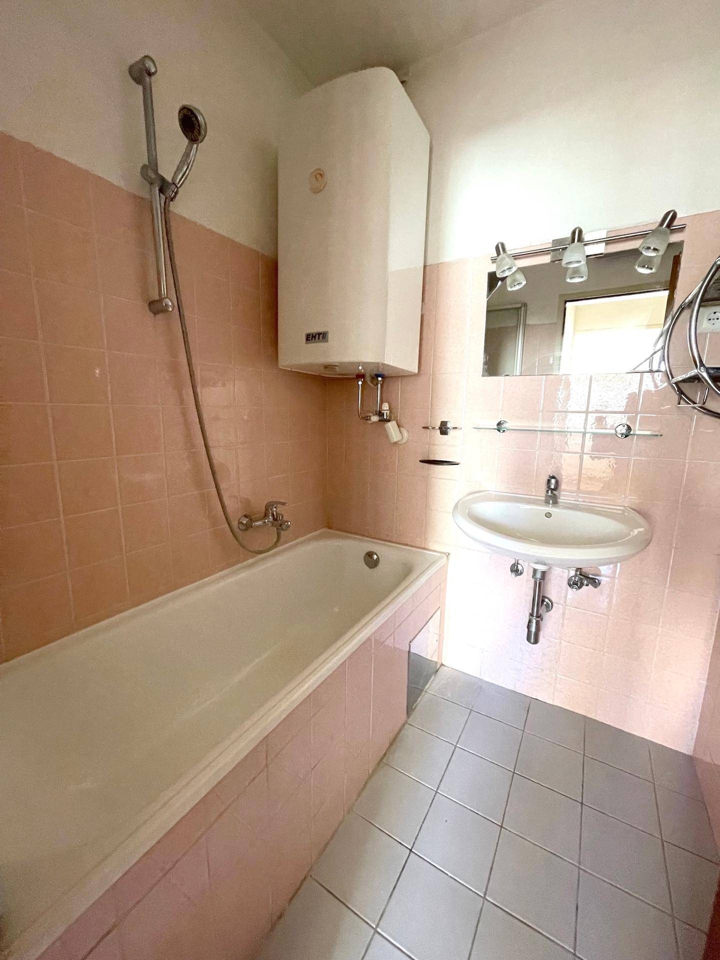 Badezimmer mit Badewanne, Dusche und rosa Fliesen im Retro-Stil.