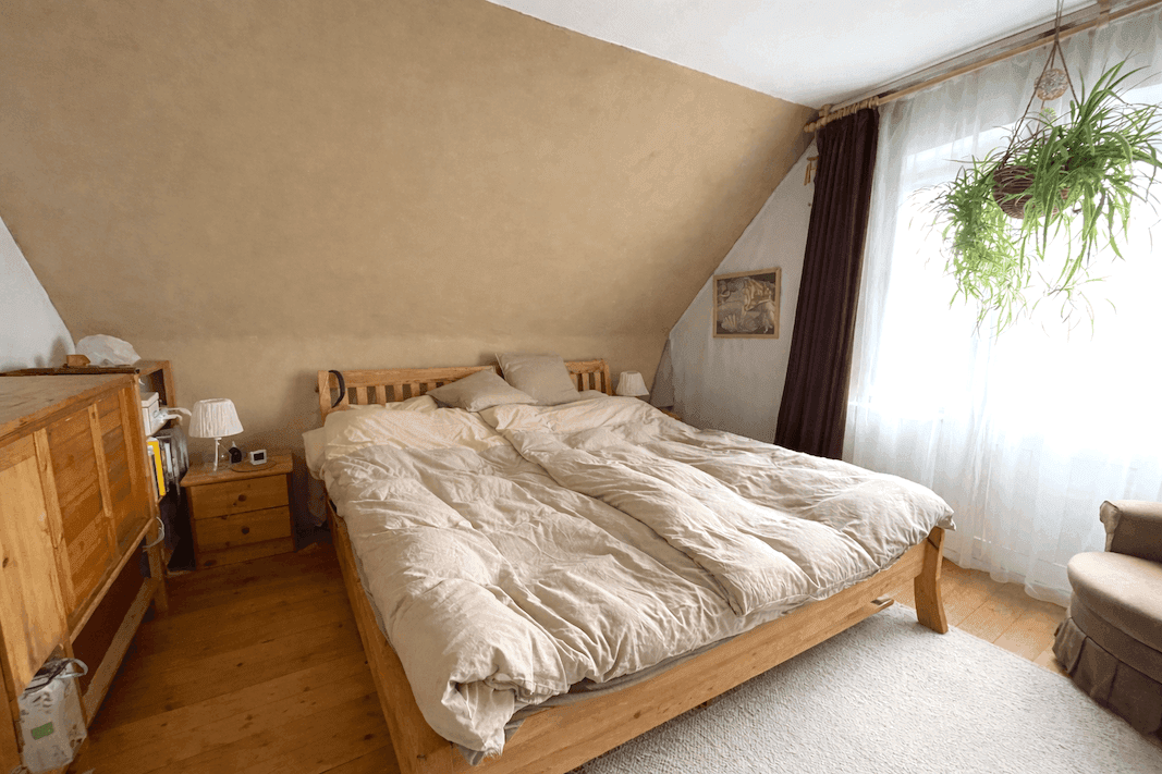 Gemütliches Schlafzimmer im Dachgeschoss mit Holzbett, Holzboden und Dachschräge.