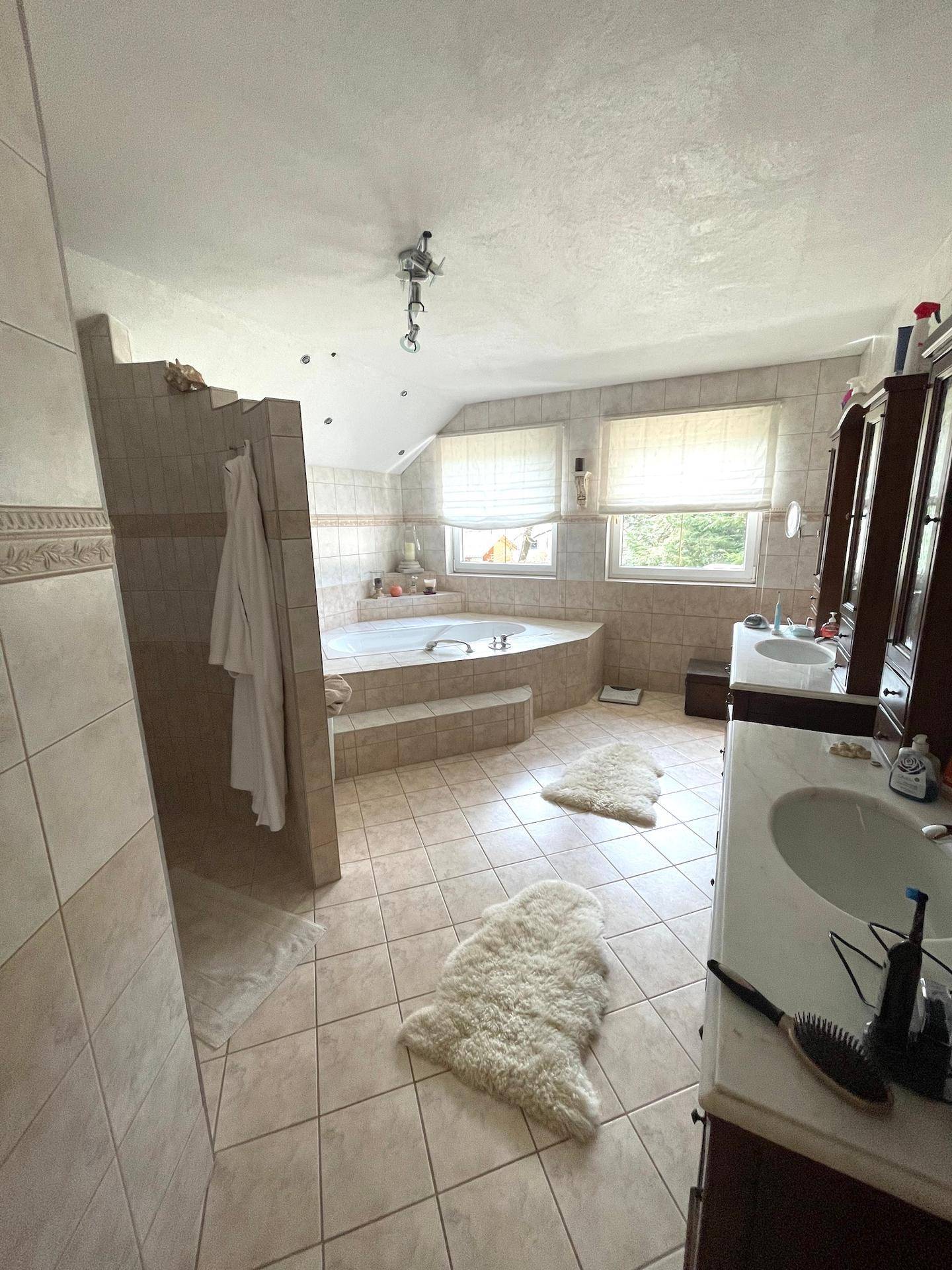 Ein geräumiges Badezimmer mit Eckbadewanne, Doppelwaschbecken und hellen Fliesen.