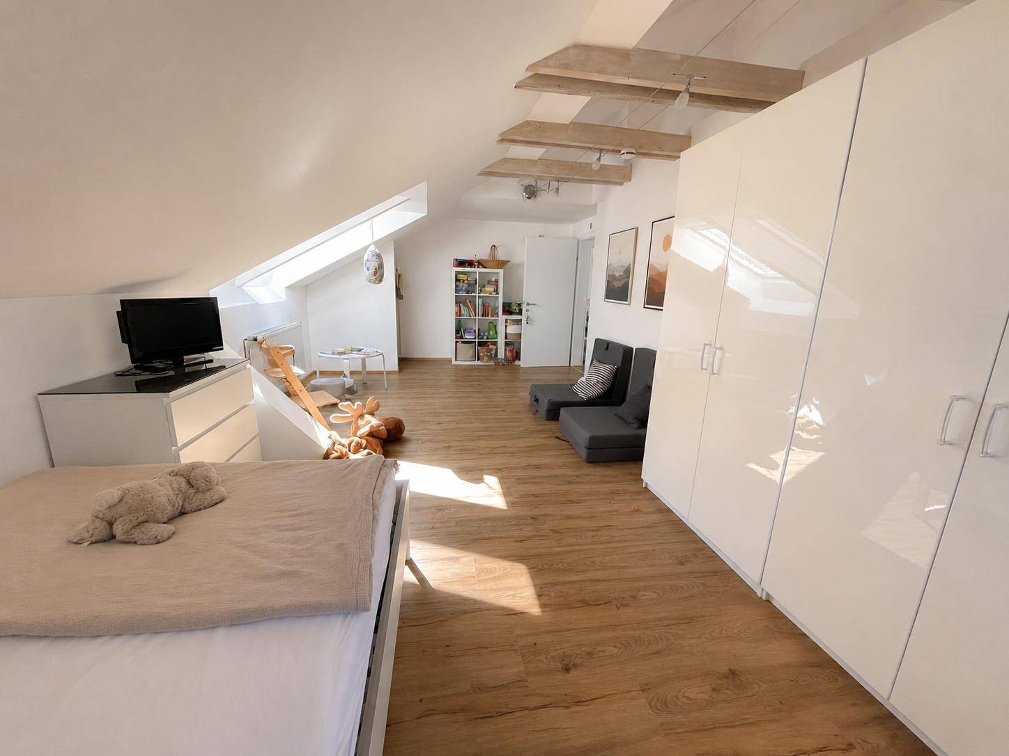 Geräumiges Schlafzimmer im Dachgeschoss mit großen weißen Kleiderschränken und Holzboden.