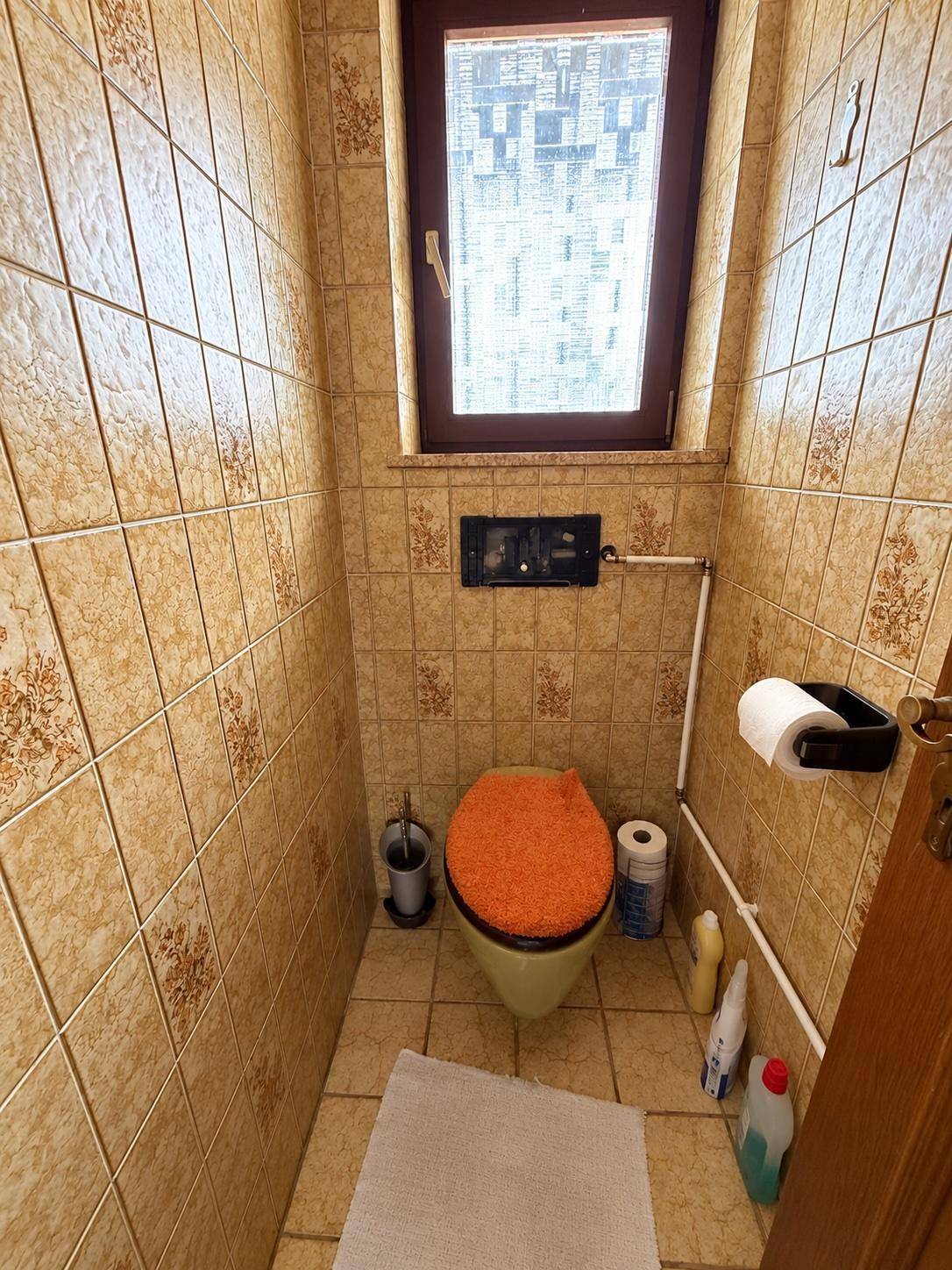 Separates WC mit Fenster und Fliesen im traditionellen Stil.