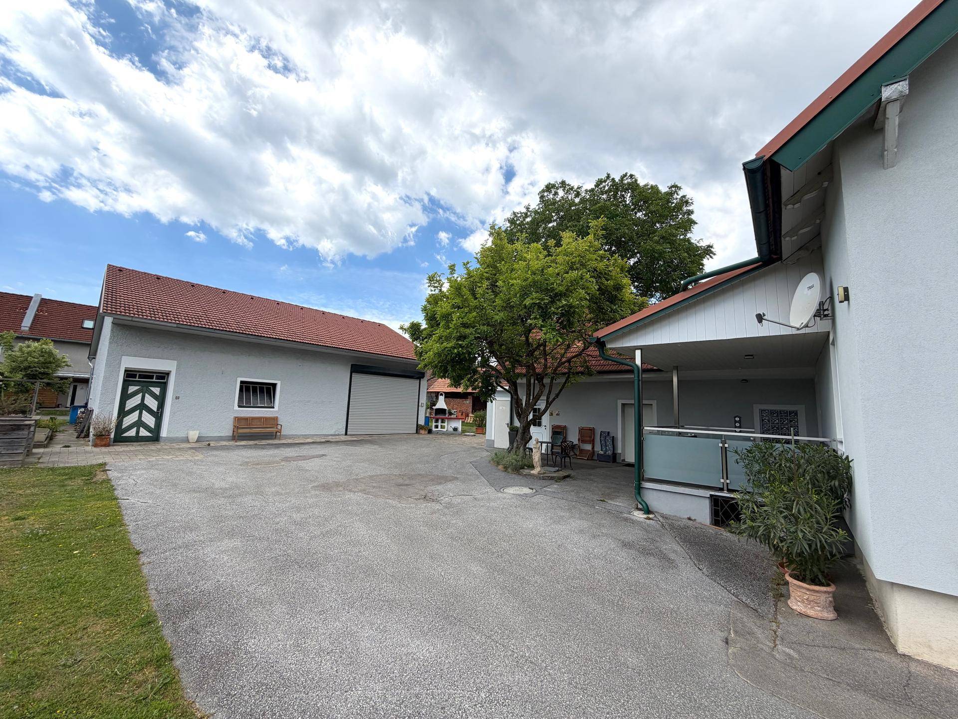 Außenansicht des Anwesens mit Haupthaus, Nebengebäude und gepflasterter Zufahrt.