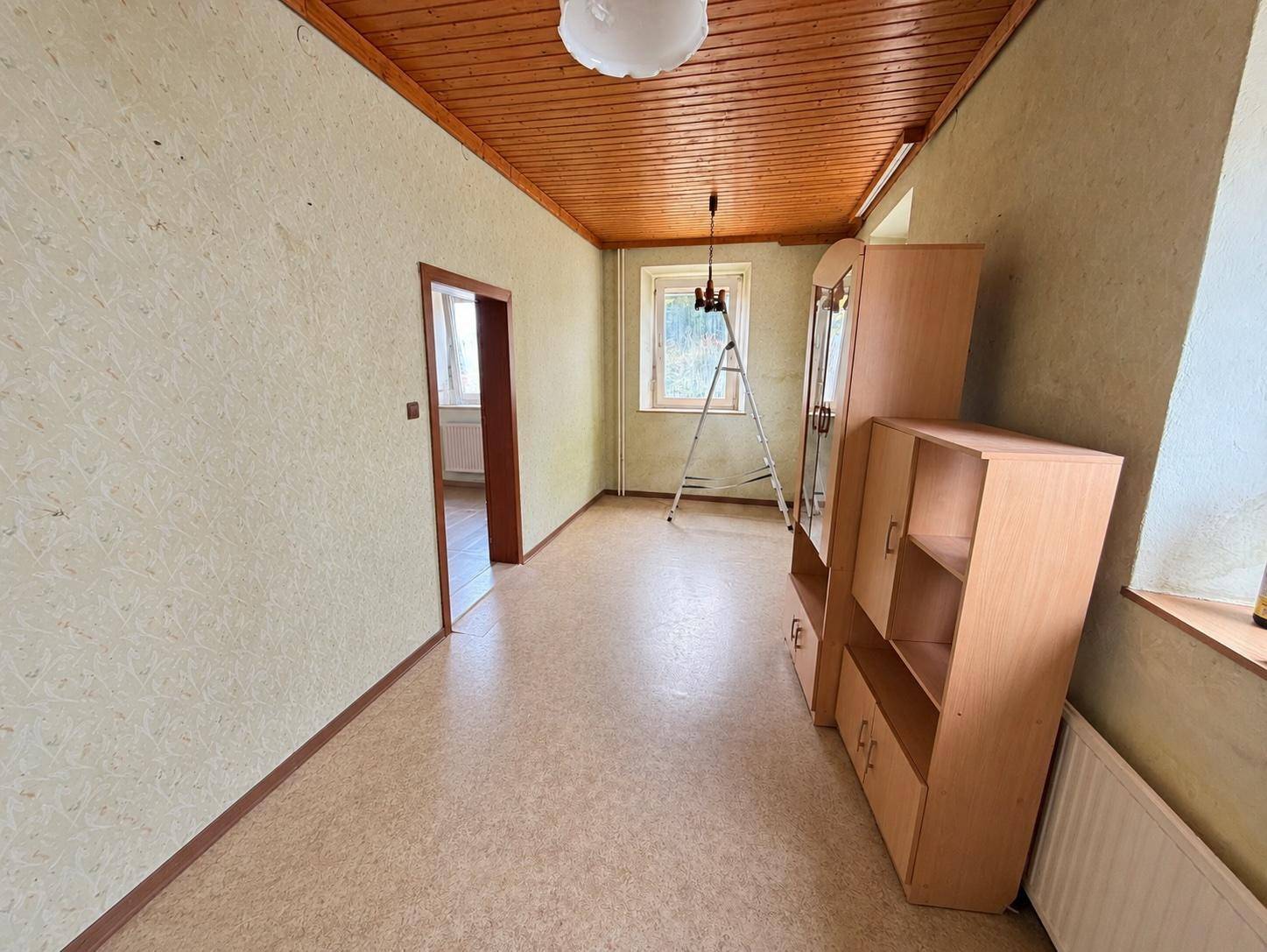 Geräumiges Zimmer mit Holzdecke, Tapeten und Blick nach draußen.