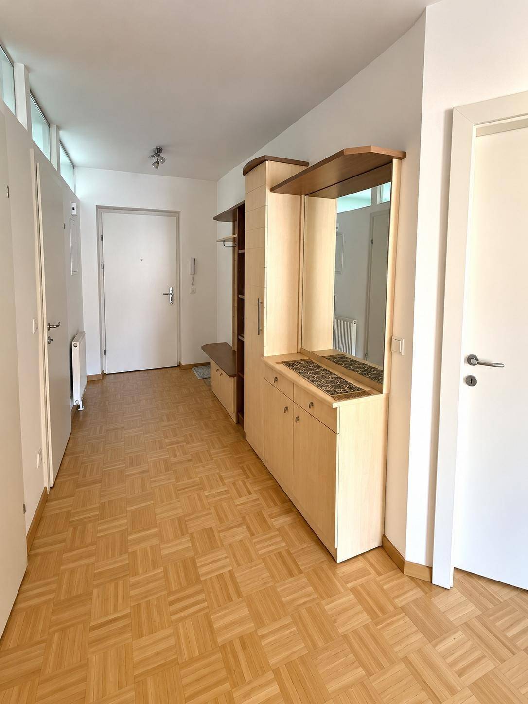 Geräumiger Flur mit Parkettboden und einem praktischen Einbauschrank mit Spiegel.