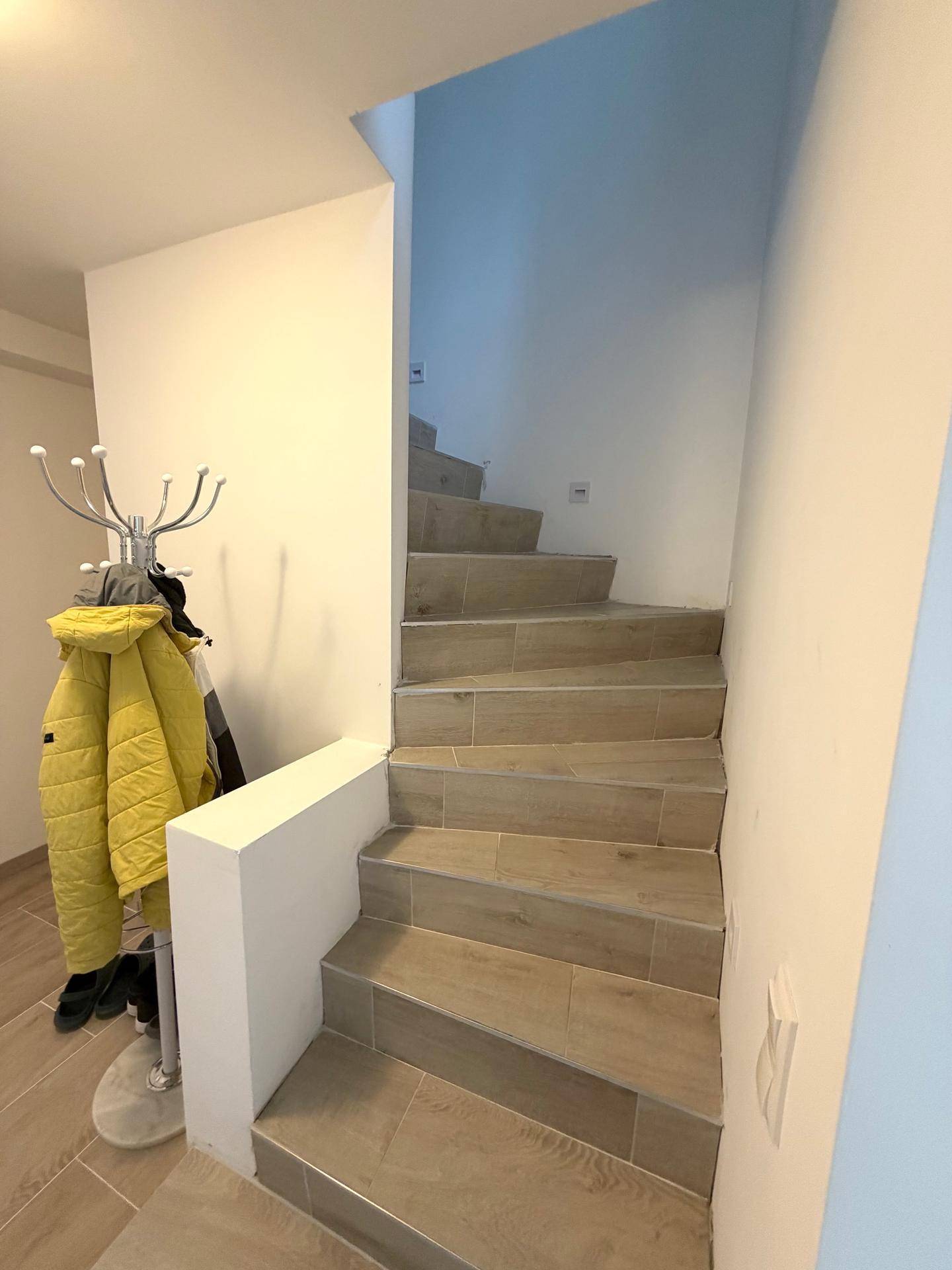 Treppenhaus mit Fliesenstufen und Garderobenständer, führt in die obere Etage.