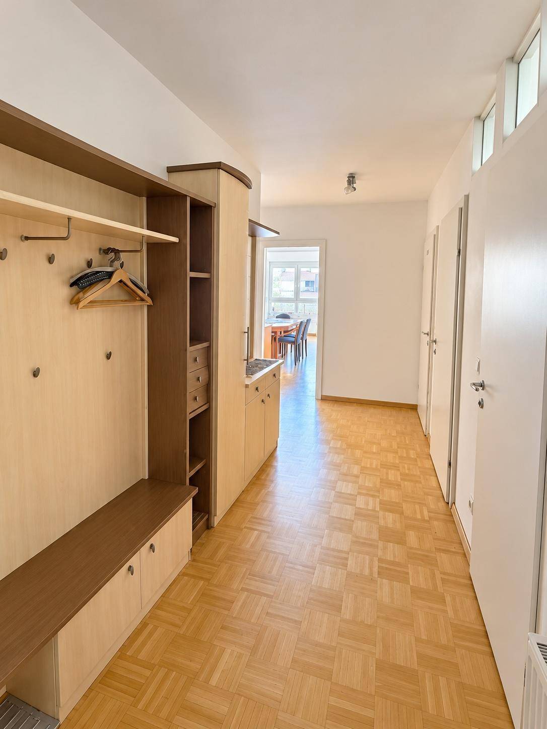 Langer Flur mit Einbauschrank und Garderobe, der zum offenen Wohnbereich führt.