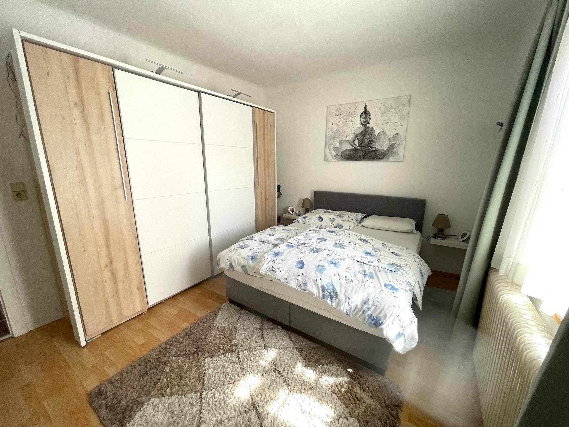 Schlafzimmer mit Laminatboden, großem Kleiderschrank und Doppelbett.