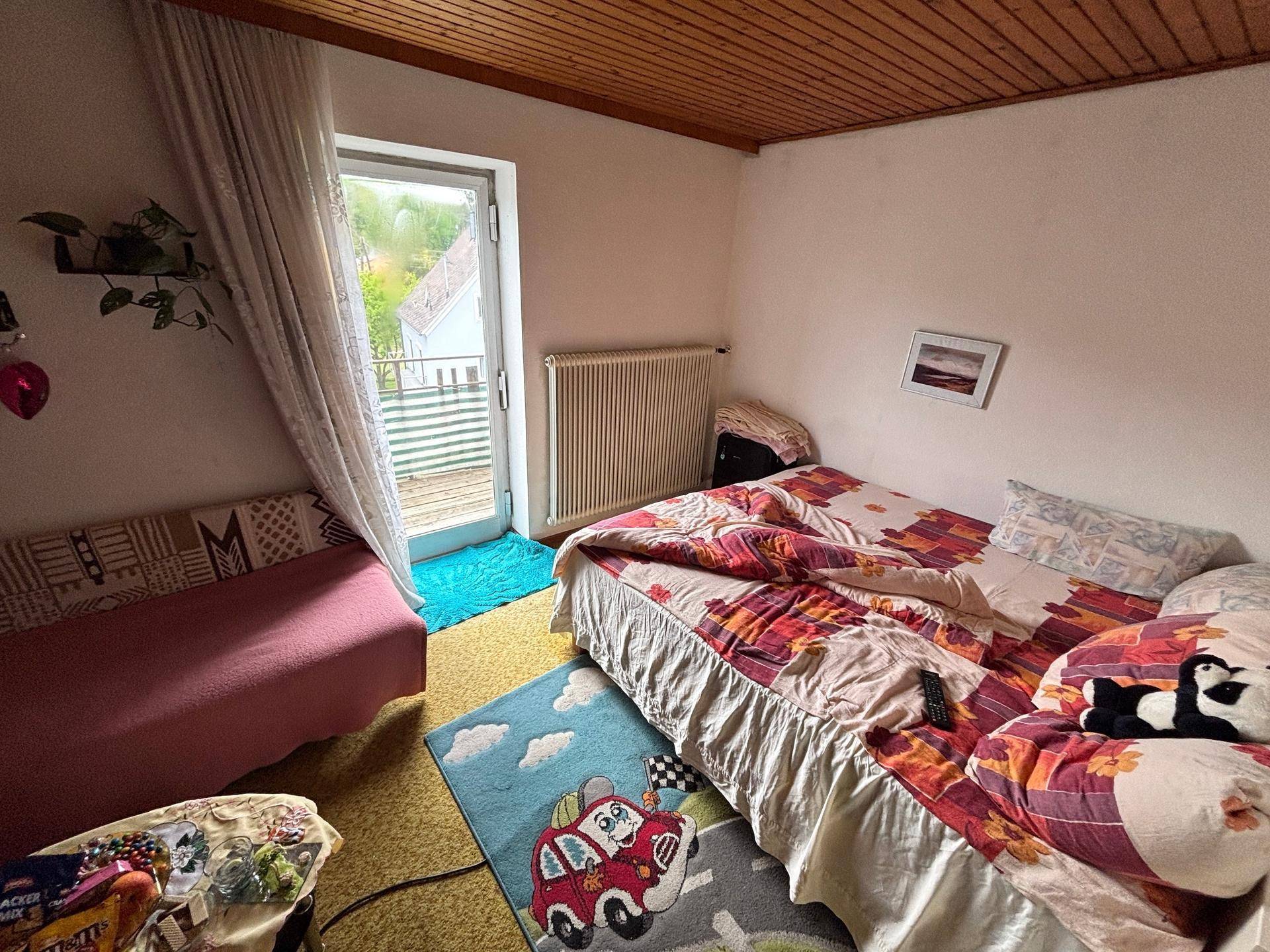 Schlafzimmer mit Doppelbett, Teppichboden und Zugang zu einem Balkon.