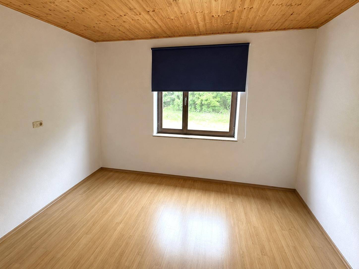 Heller Raum mit Holzdeckenverkleidung und Laminatboden, ideal für verschiedene Nutzungen.