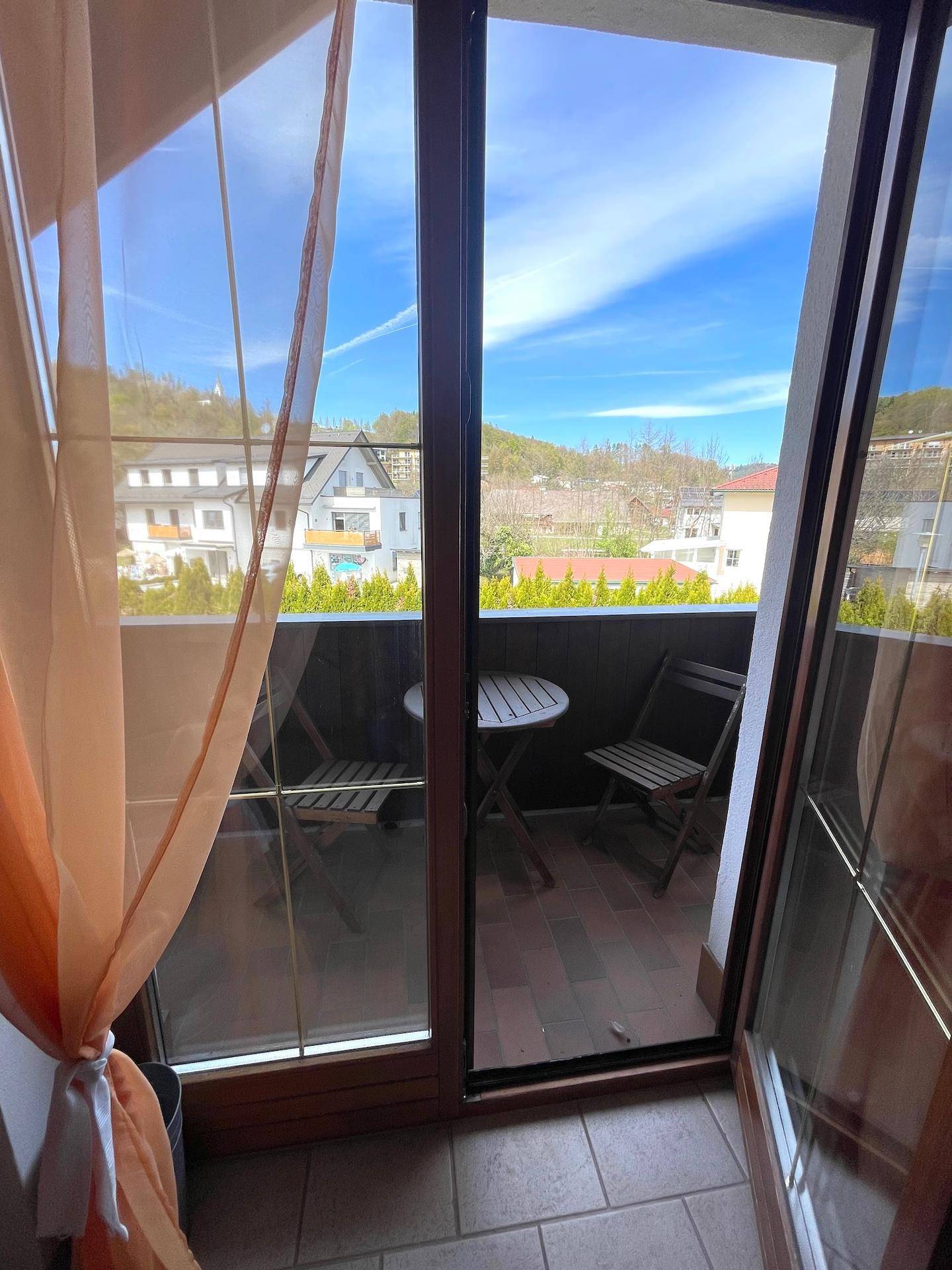 Ein kleiner Balkon mit Sitzgelegenheiten und Blick auf die grüne Umgebung.