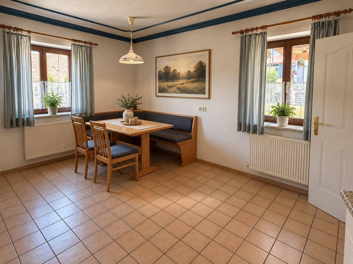 Essbereich in der Küche mit Holztisch, Eckbank und Blick ins Grüne durch die Fenster.
