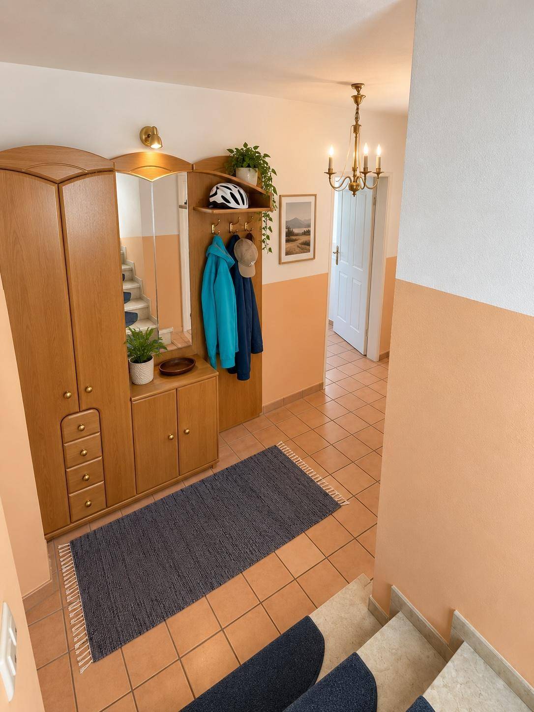 Eingangsbereich mit Garderobe, Spiegel und Treppe, die in die oberen Etagen führt.