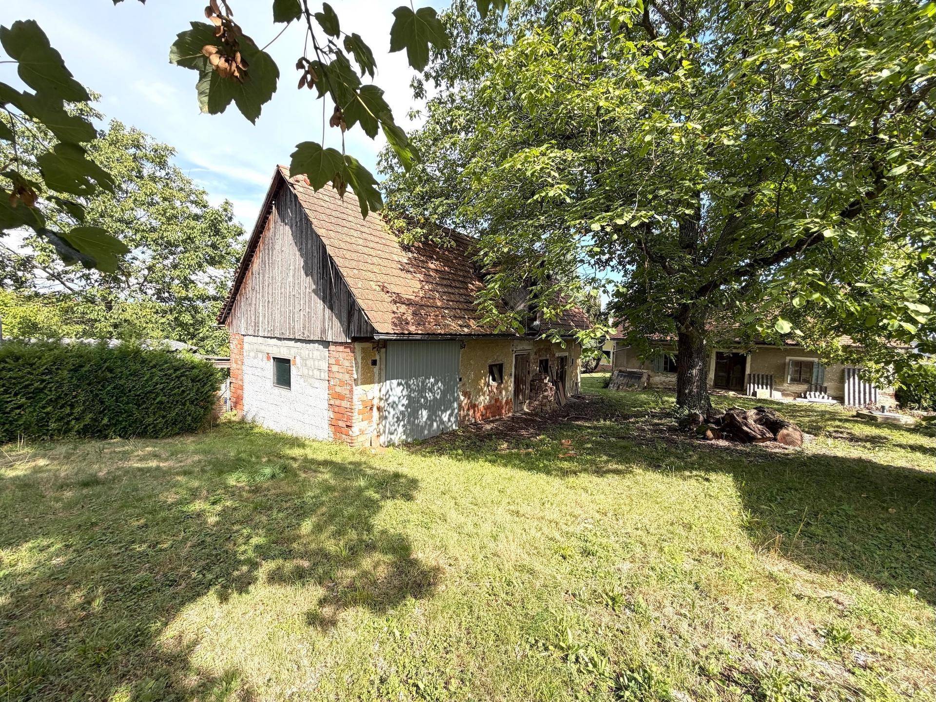 Rückansicht eines älteren Hauses mit Ziegeldach und Nebengebäude in ländlicher Umgebung.