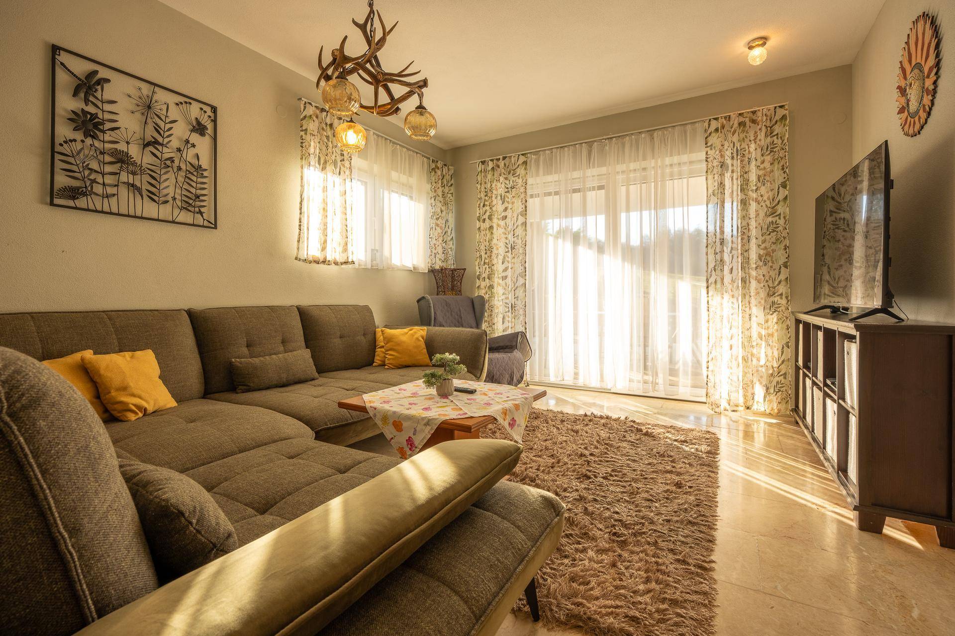 Gemütliches Wohnzimmer mit großem Ecksofa, Teppich und Zugang zur Terrasse.