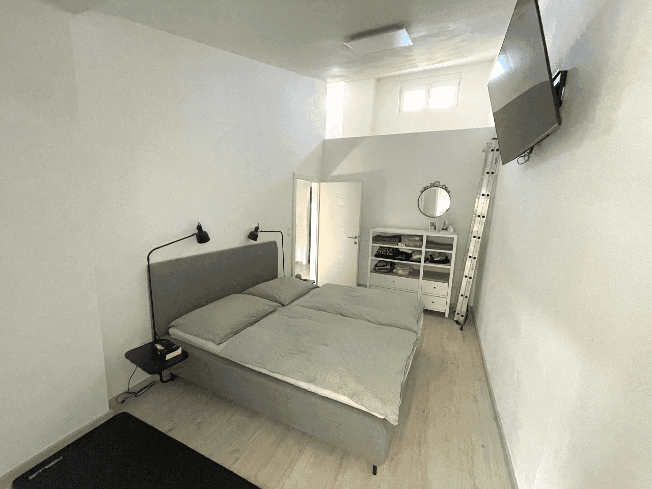 Schlafzimmer mit Doppelbett, TV und offener Gestaltung, modern eingerichtet.