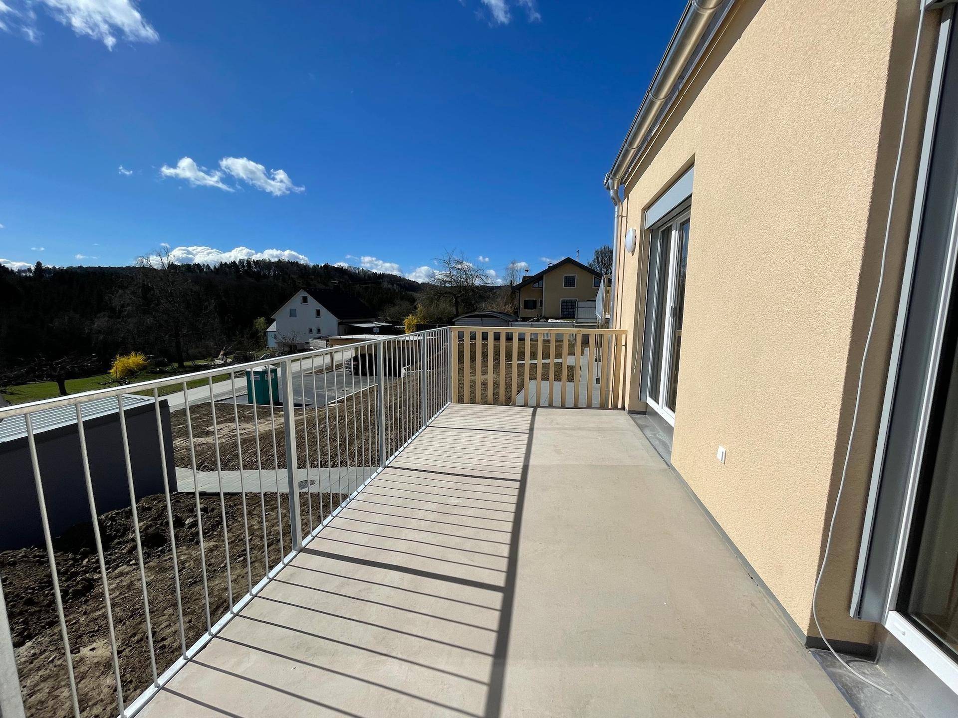 Geräumiger Balkon mit Metallgeländer und weitem Blick über die Landschaft.