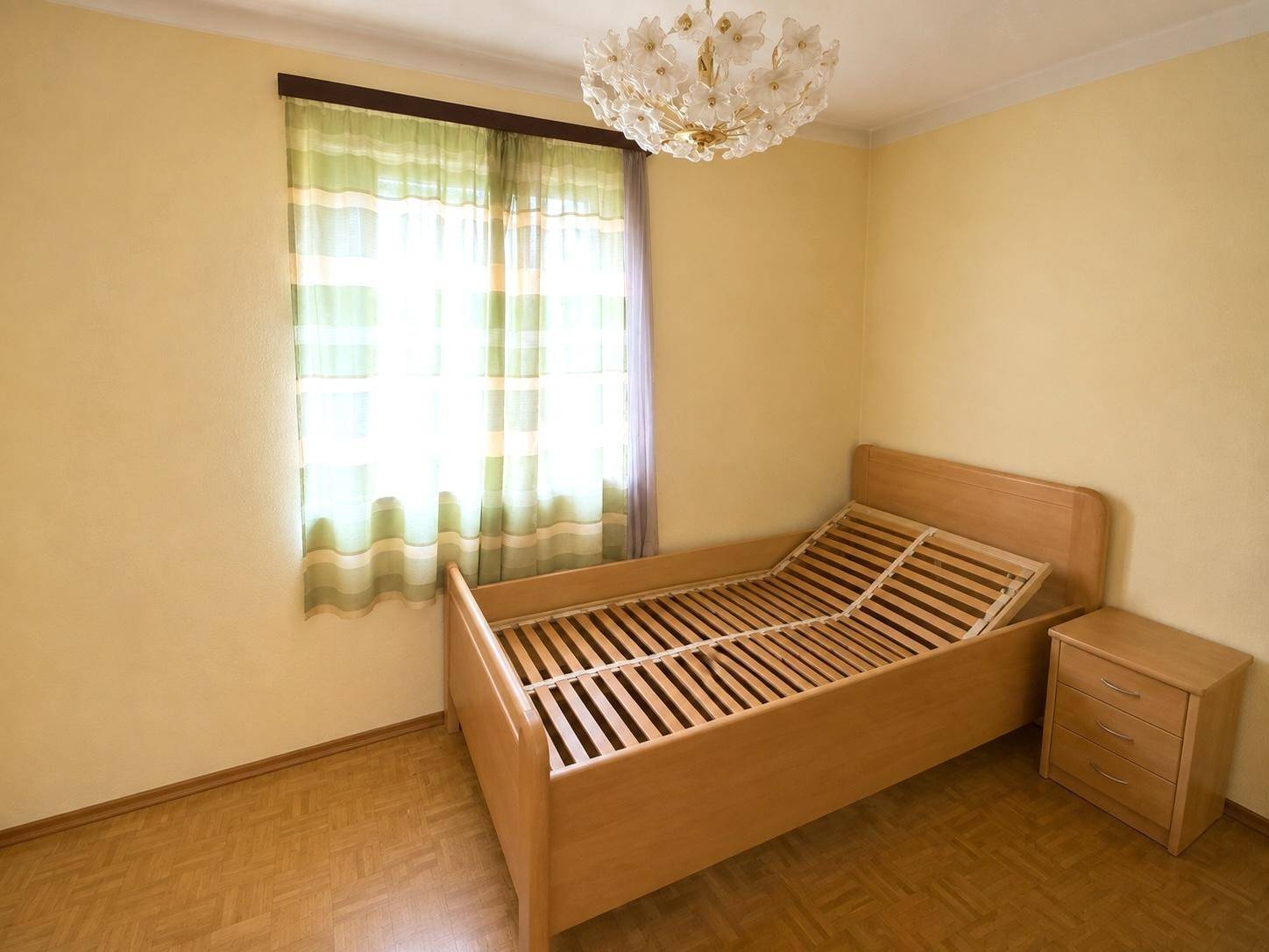 Gemütliches Schlafzimmer mit Einzelbett, Nachttisch und hellem Holzboden.