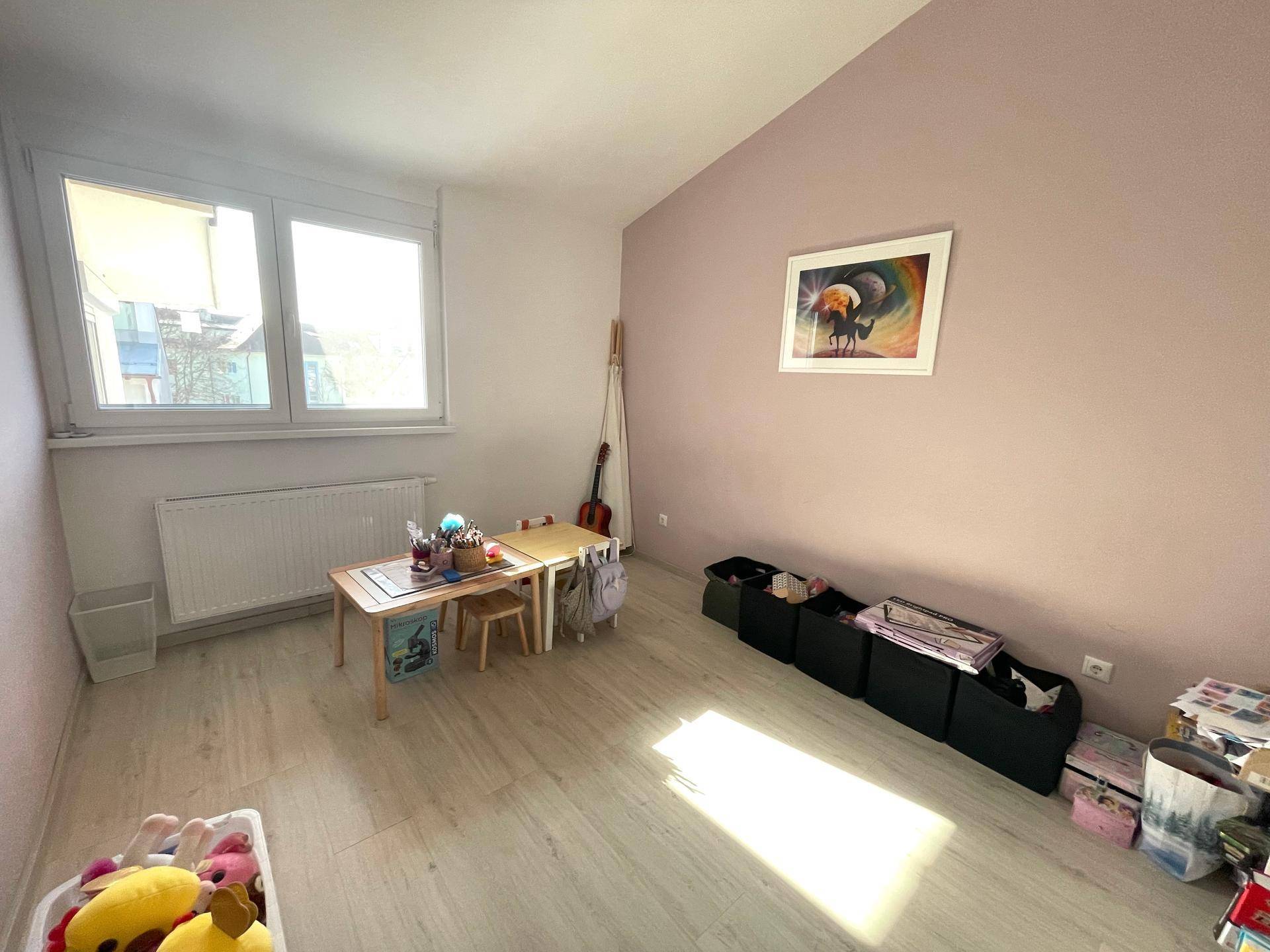 Helles Zimmer mit Kindermöbeln und Fenster, ideal als Spiel- oder Arbeitszimmer.